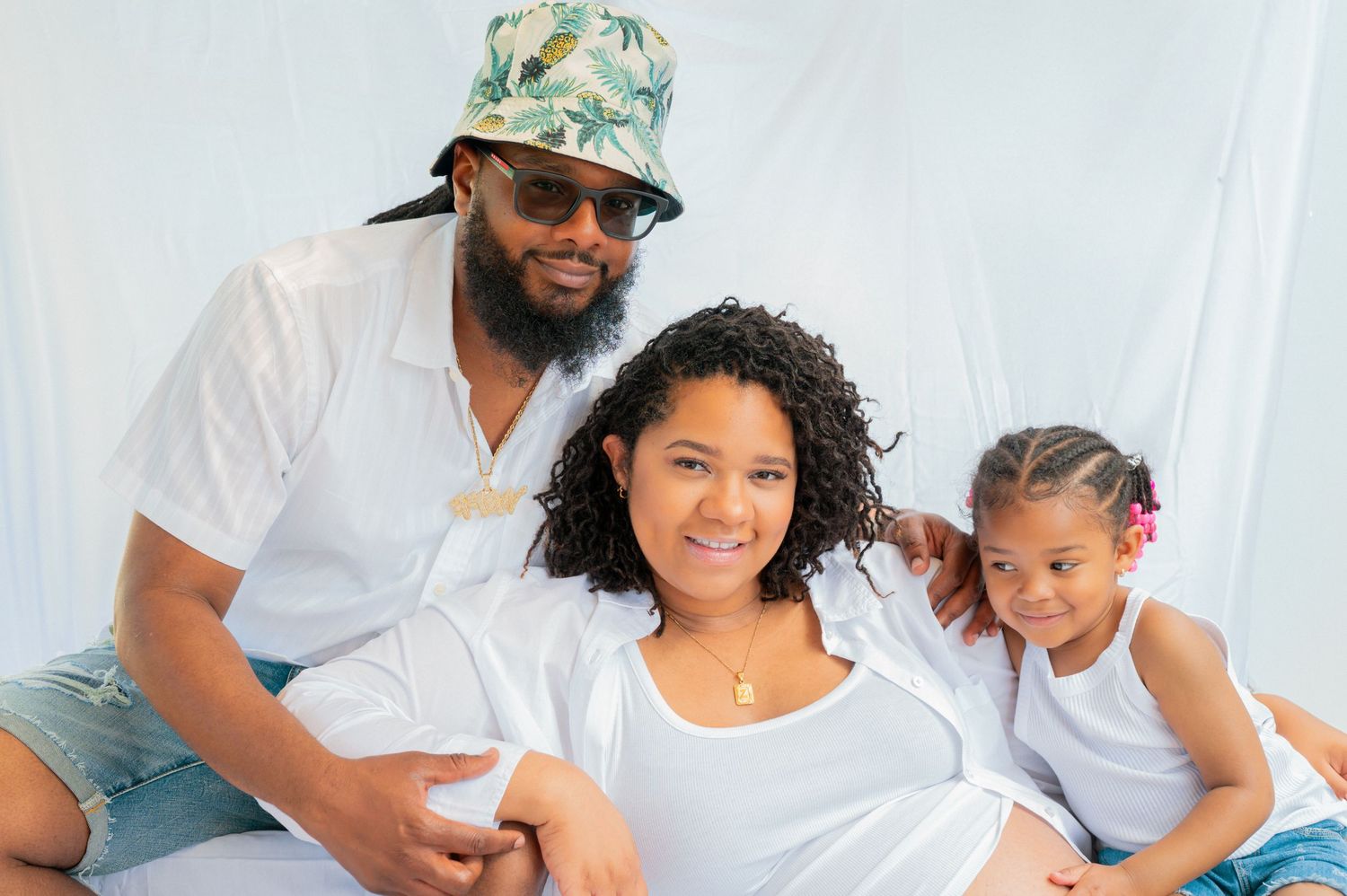 A family sits together wearing white tops against a light background.