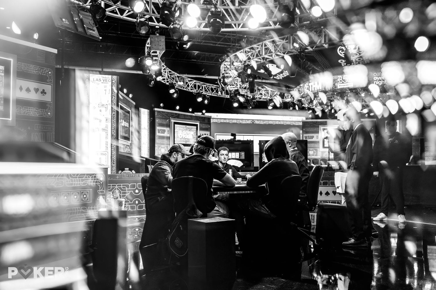 Black and white photograph shows city street scene at night with lit string lights overhead creating a festive ambiance.