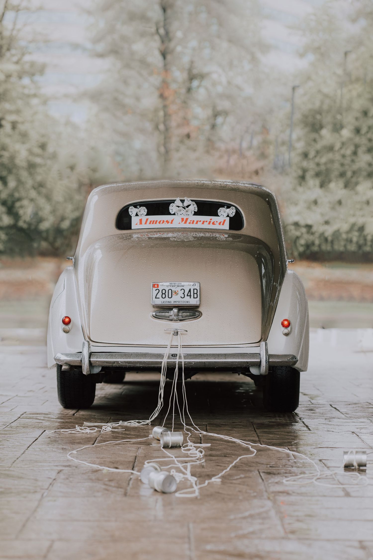 Vintage white getaway car decorated with just married sign and tin cans for wedding celebration.