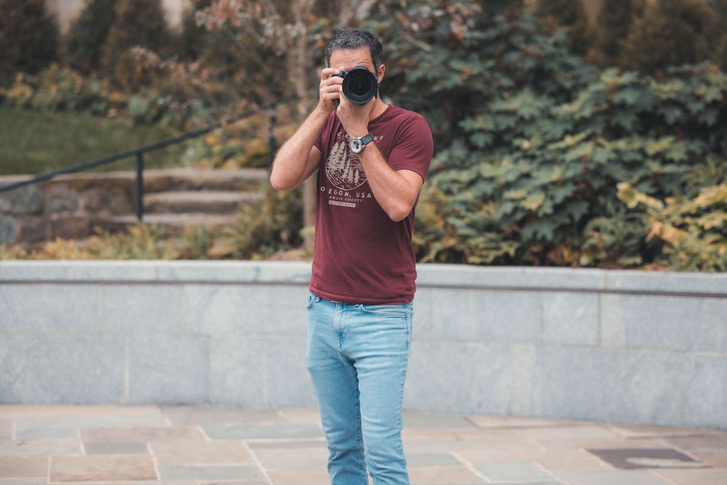 Photographer in casual attire taking pictures outdoors.