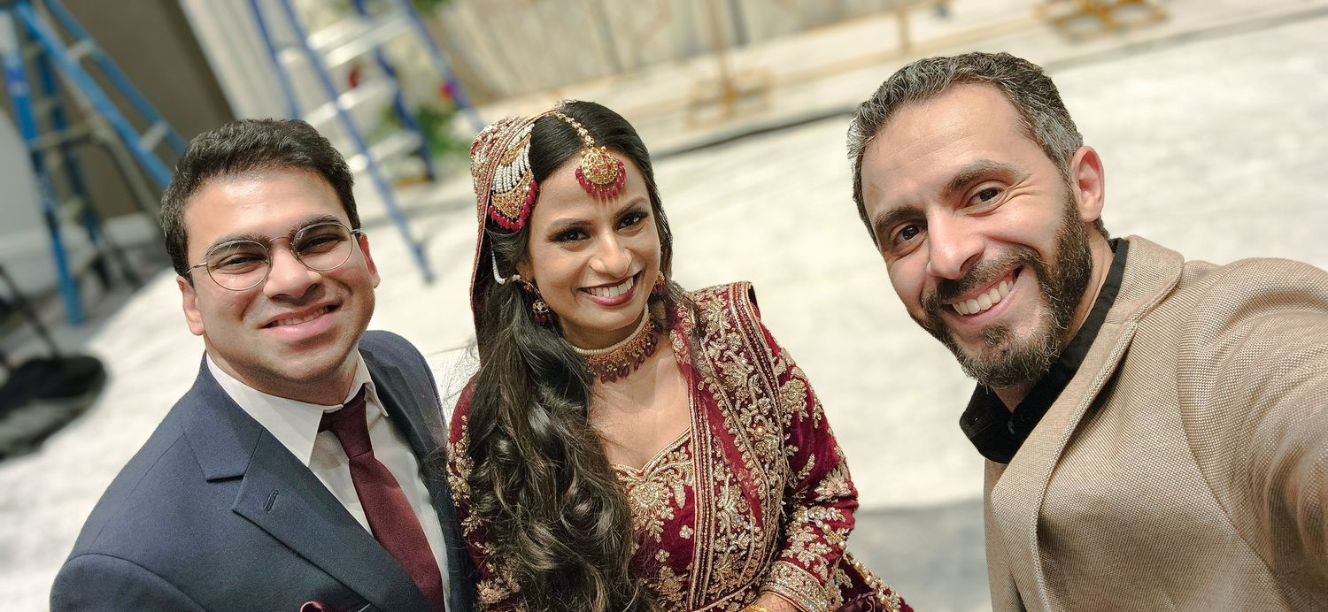 Wedding guests posing together in traditional Indian and Western attire outside a building.