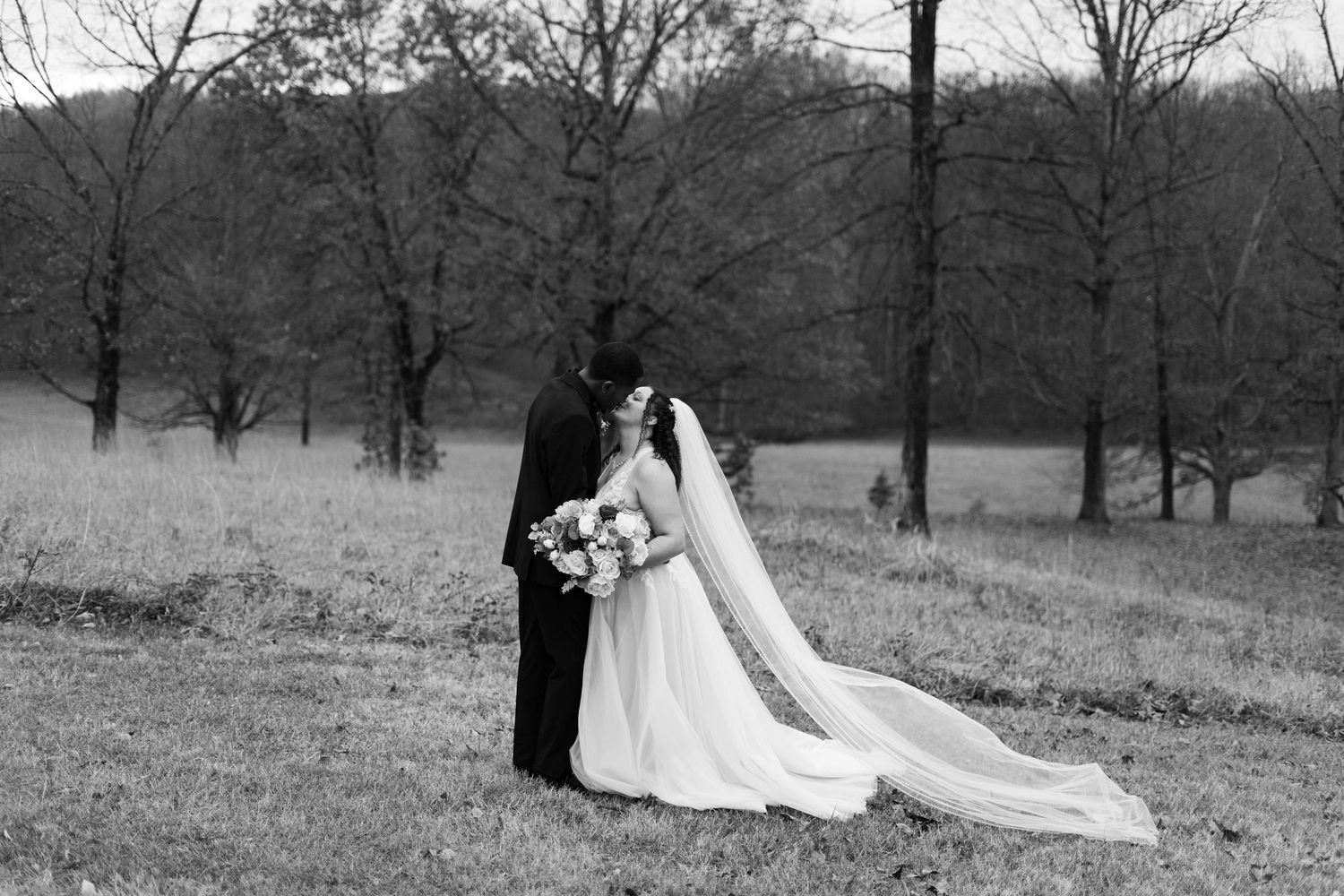Black and white wedding portrait of couple in scenic outdoor setting.