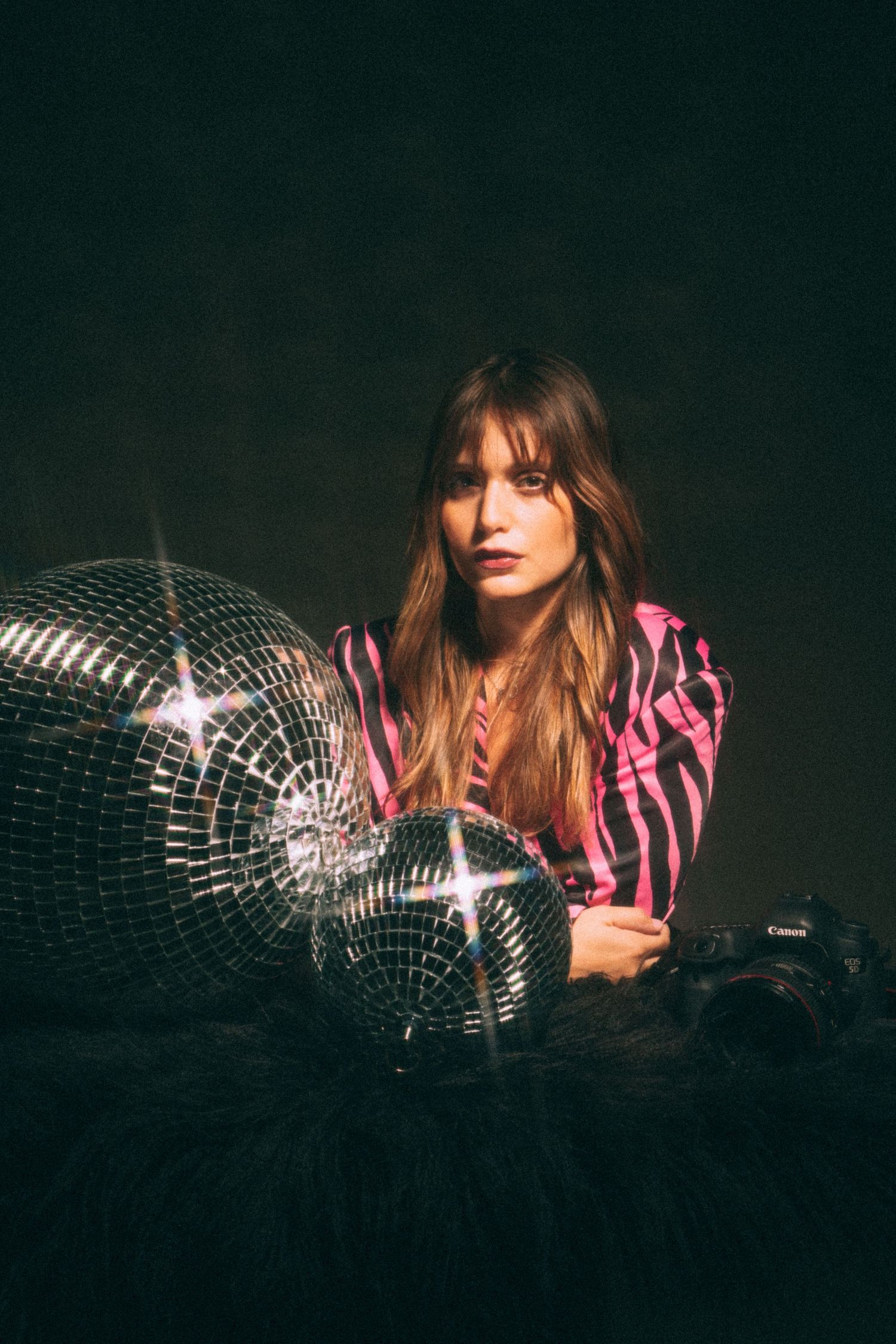 A moody studio portrait with disco ball and pink zebra print styling.