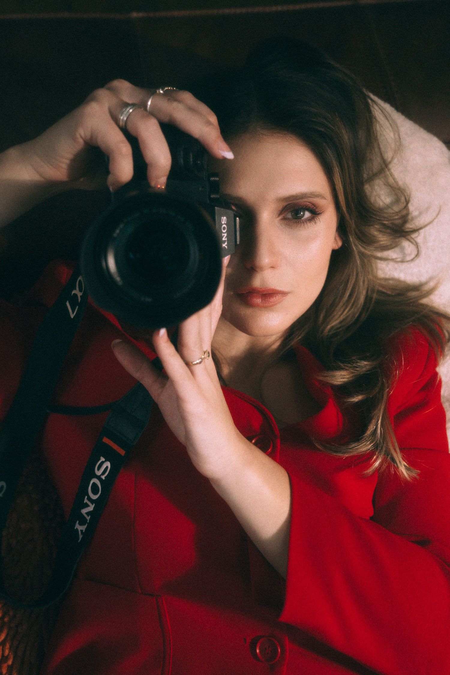 Branding Photography Sessions capture an entrepreneur in a red jacket holding a DSLR camera in dramatic lighting, showcasing storytelling.