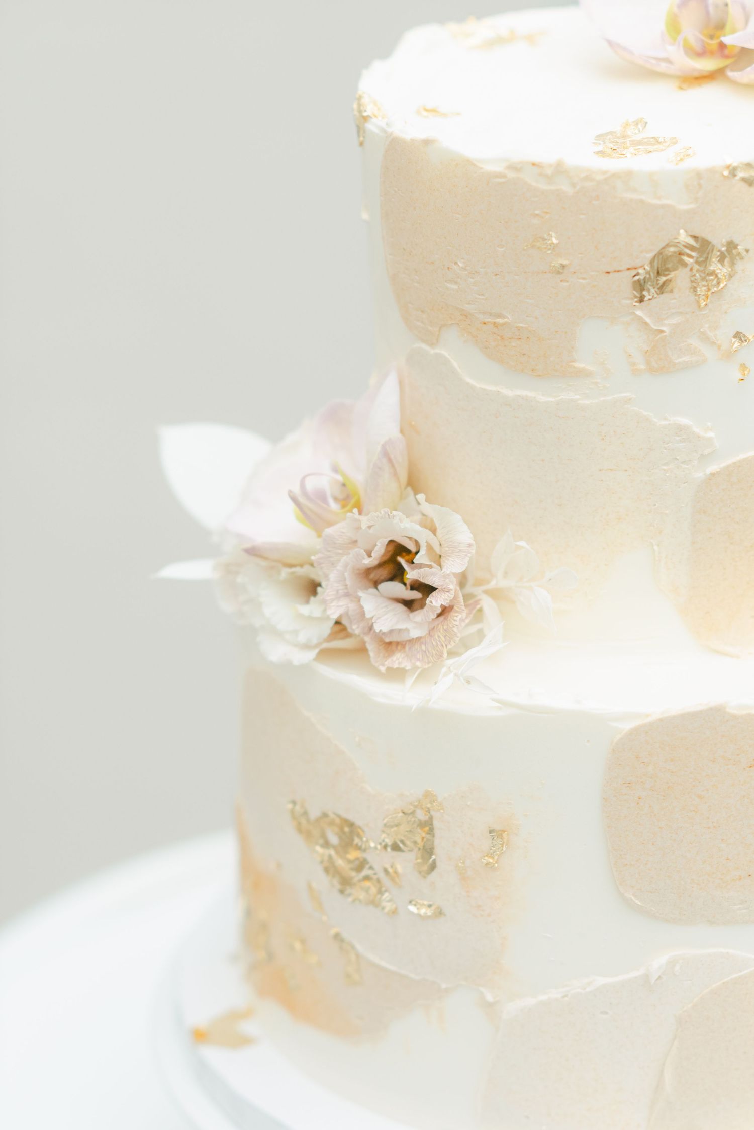Close-up of white buttercream wedding cake with delicate floral accents. - Mae District Chicago Wedding