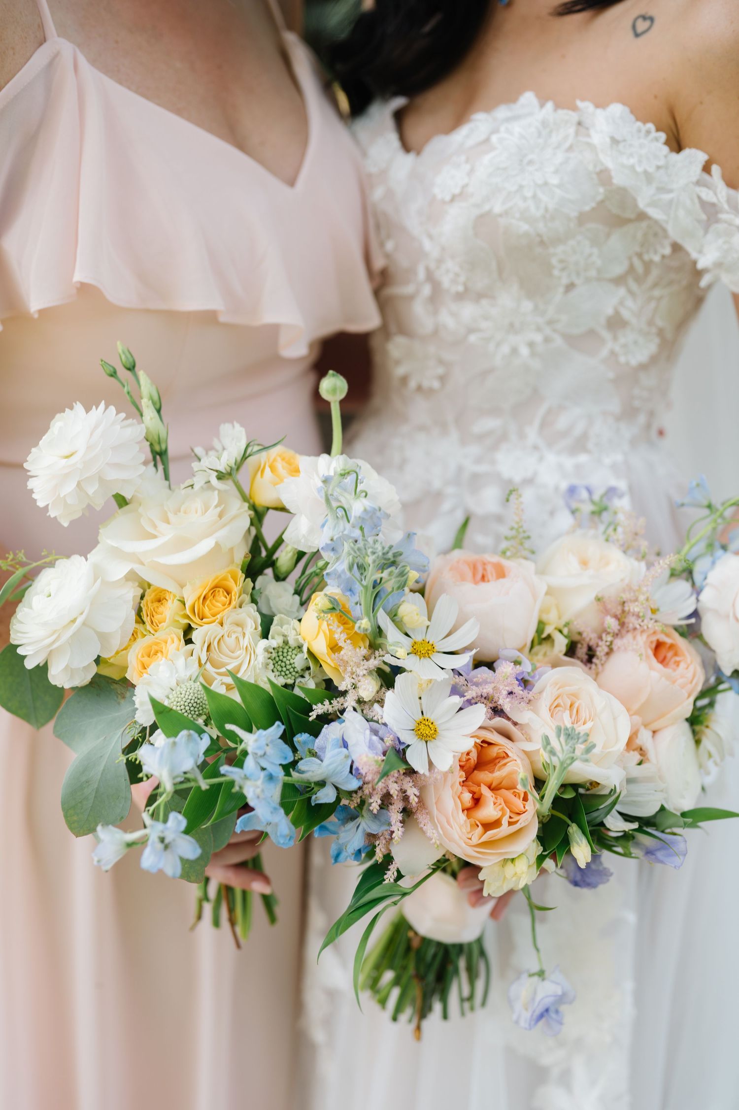 Delicate spring wedding bouquet featuring peach roses, white peonies and blue forget-me-nots.