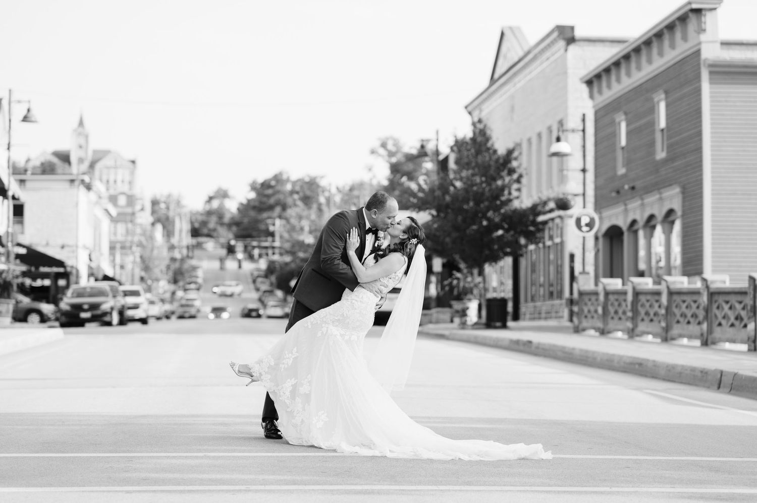 A romantic dip pose between a bride and groom embracing in the middle of a city street in black and white.