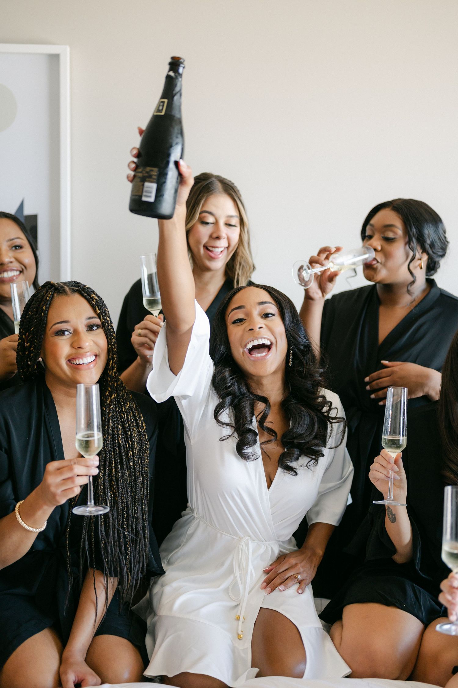 Bridesmaids celebrate joyfully with champagne during wedding preparations. - Mae District Chicago Wedding