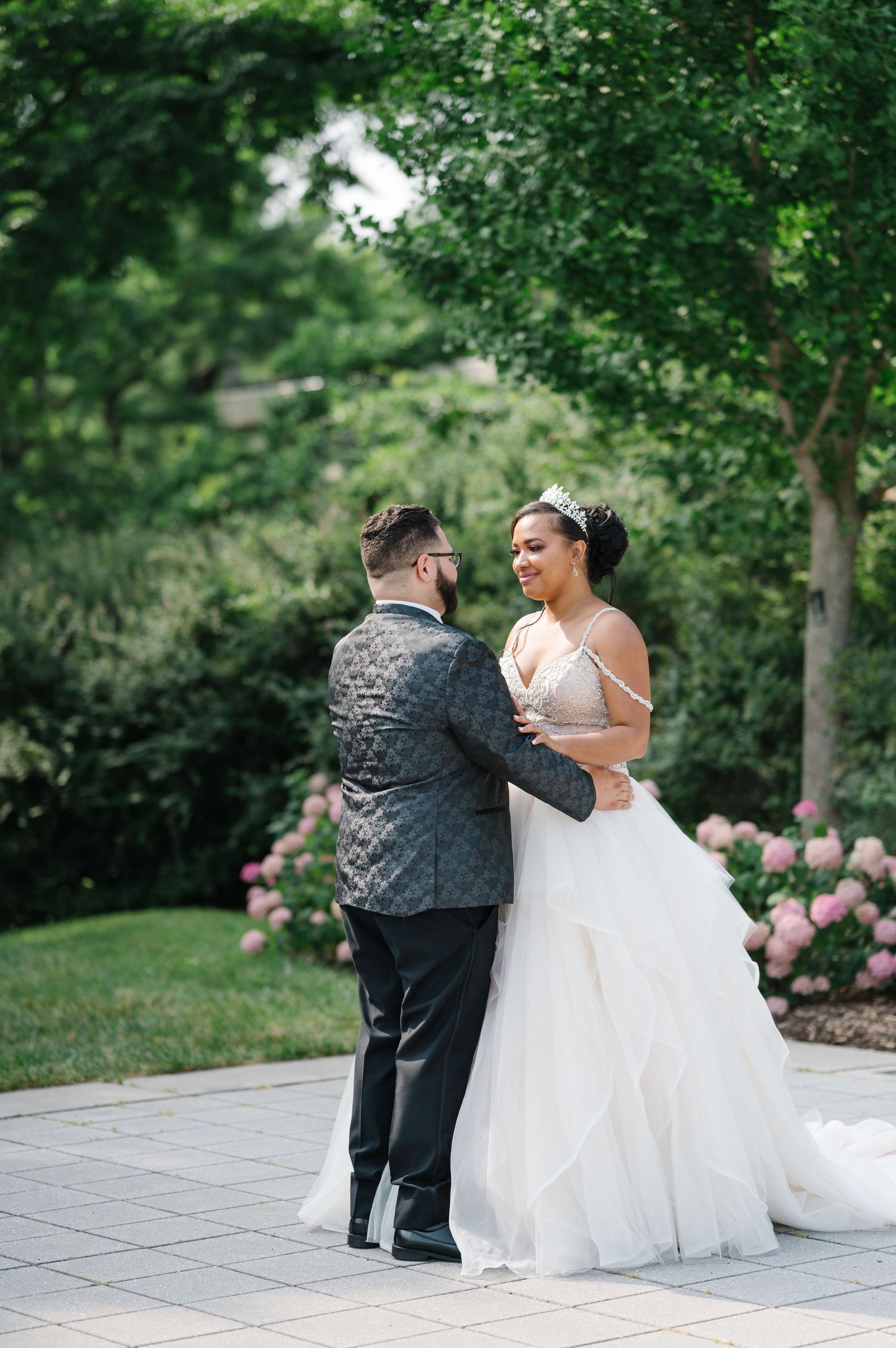 A joyful couple shares their first dance outdoors at a summer garden wedding ceremony.