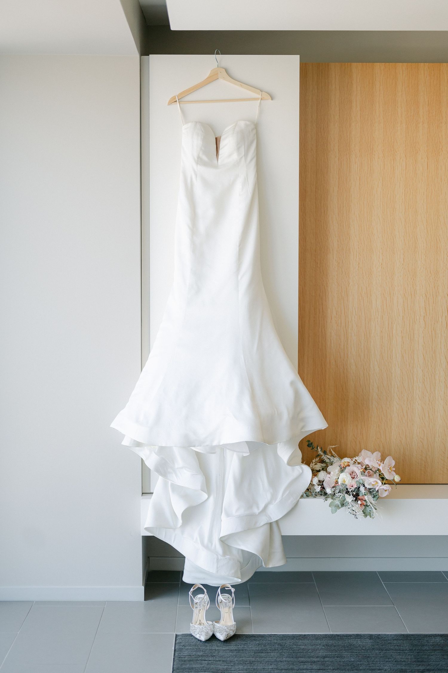 Classic white wedding dress hanging on display with bridal shoes below. - Mae District Chicago Wedding