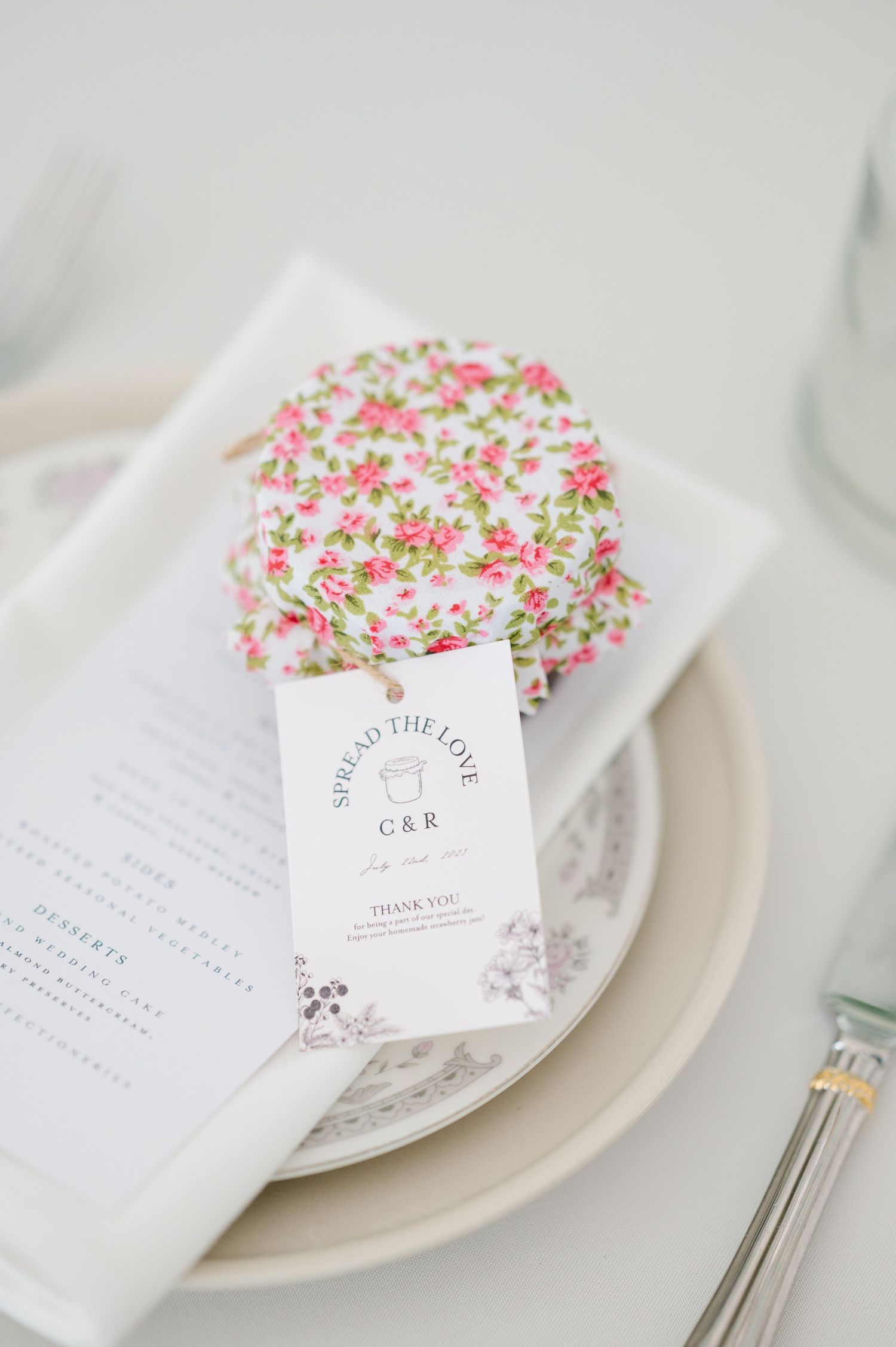 Elegant white plate setting with floral sprinkle cookie and wedding invitation card featuring delicate pink details.