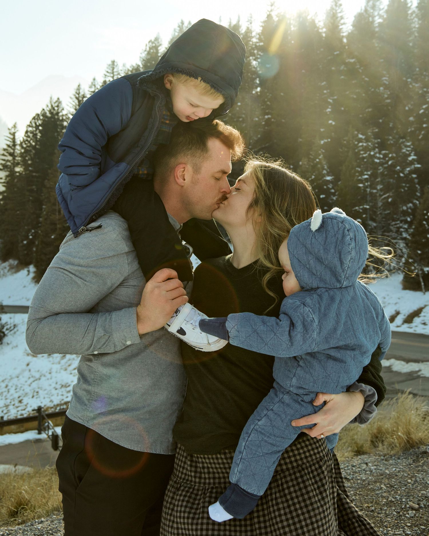 Family sharing an intimate moment together in snowy mountain setting at sunset.