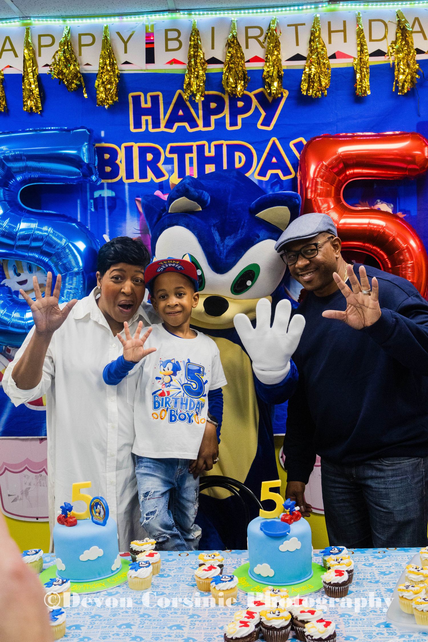 Birthday celebration with blue number balloons and mascot character at kids party.