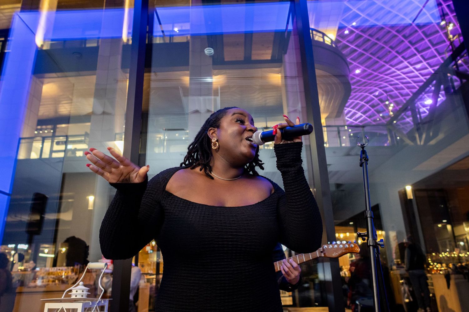 Singer performs passionately under blue and purple lighting at indoor venue.