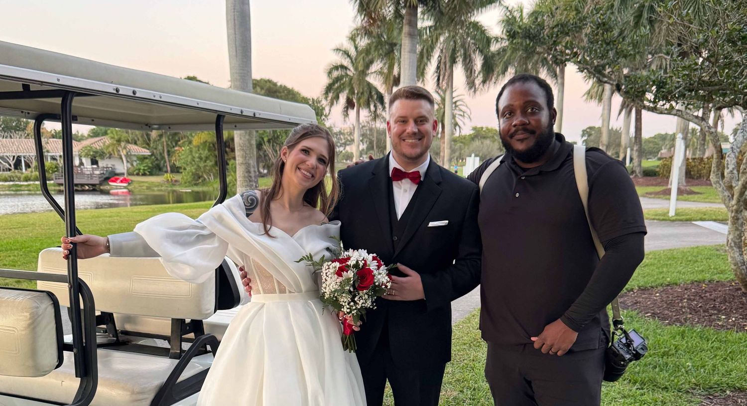 Wedding party members pose together next to a golf cart with palm trees in the background.