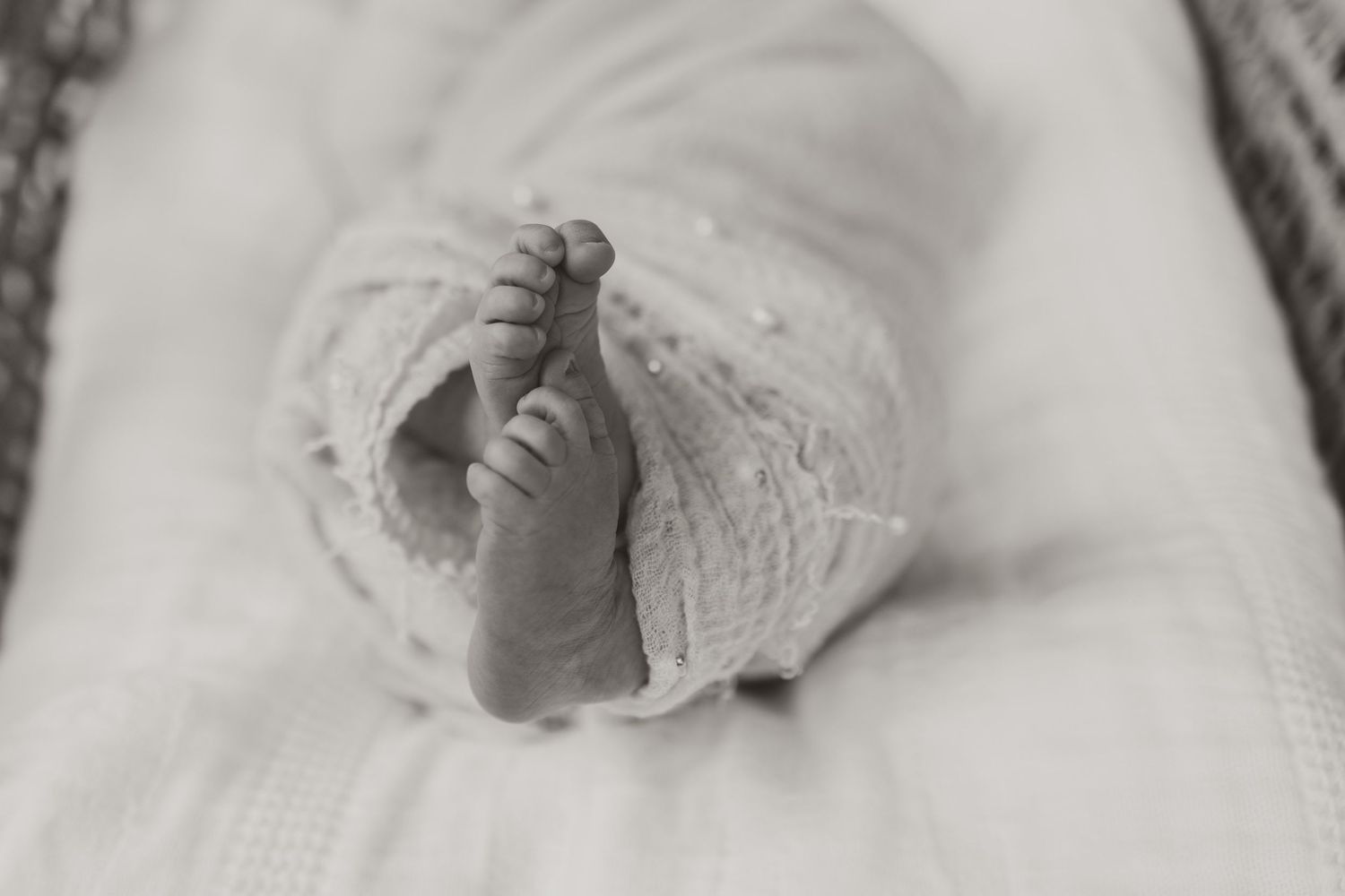 A baby's hand reaching out and grasping towards the camera in black and white.