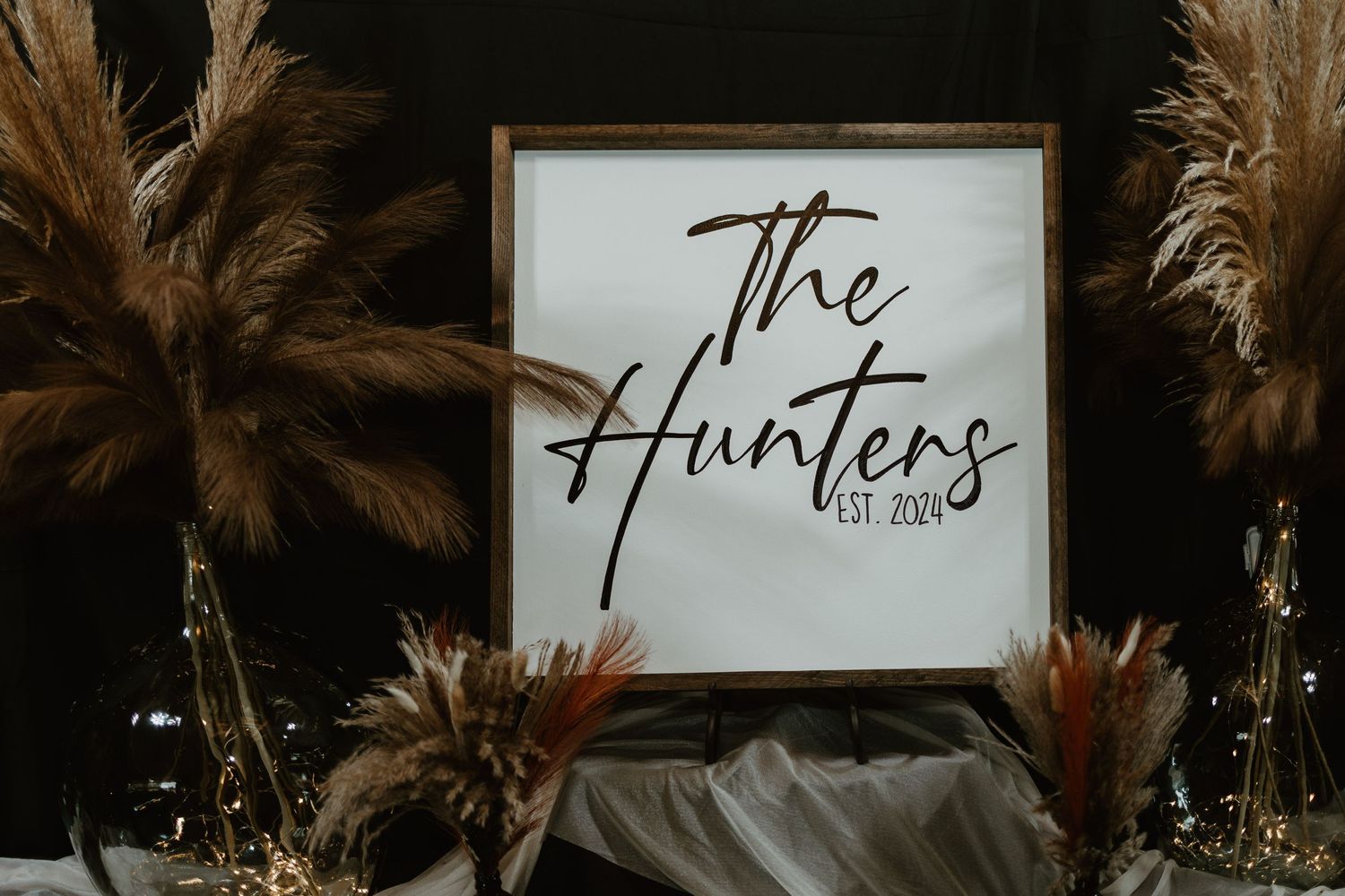 Rustic wooden signs with elegant script lettering displayed at a wedding venue with palm fronds in the background.