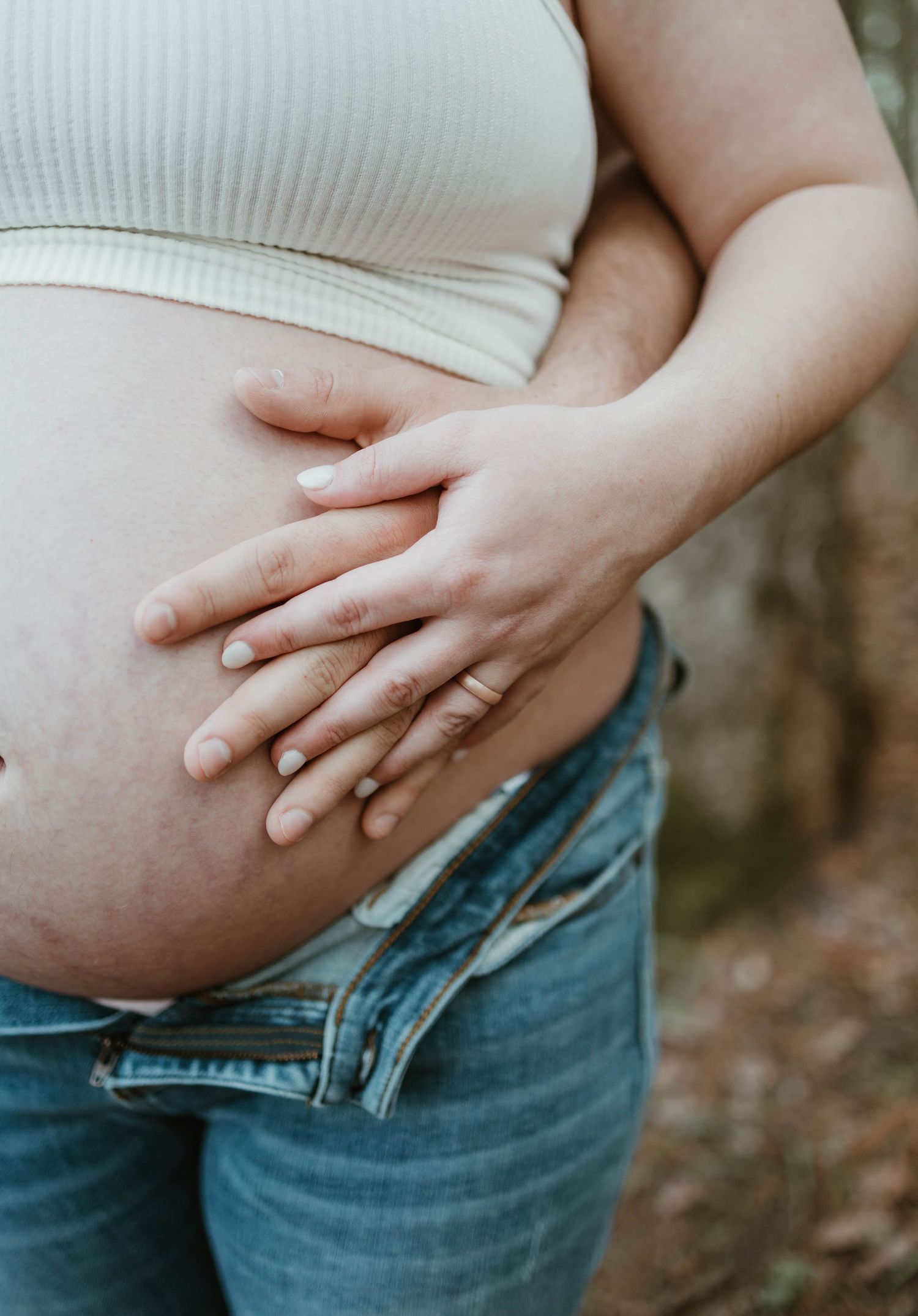 Multiple photos showing a close-up of a pregnant belly covered in a white top with hands gently resting on it in different poses.