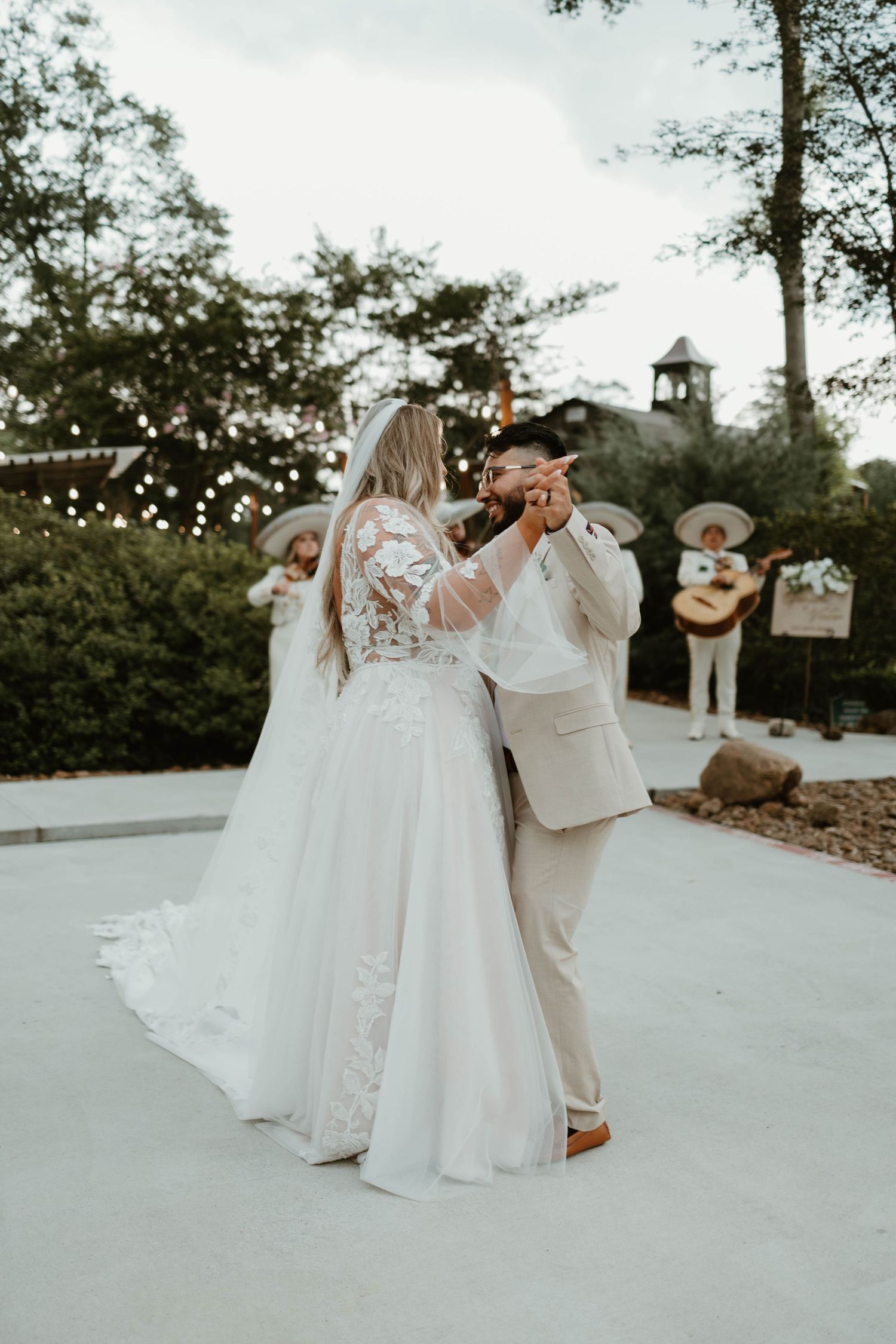 A couple shares their first dance on an outdoor patio during a romantic wedding celebration at dusk.