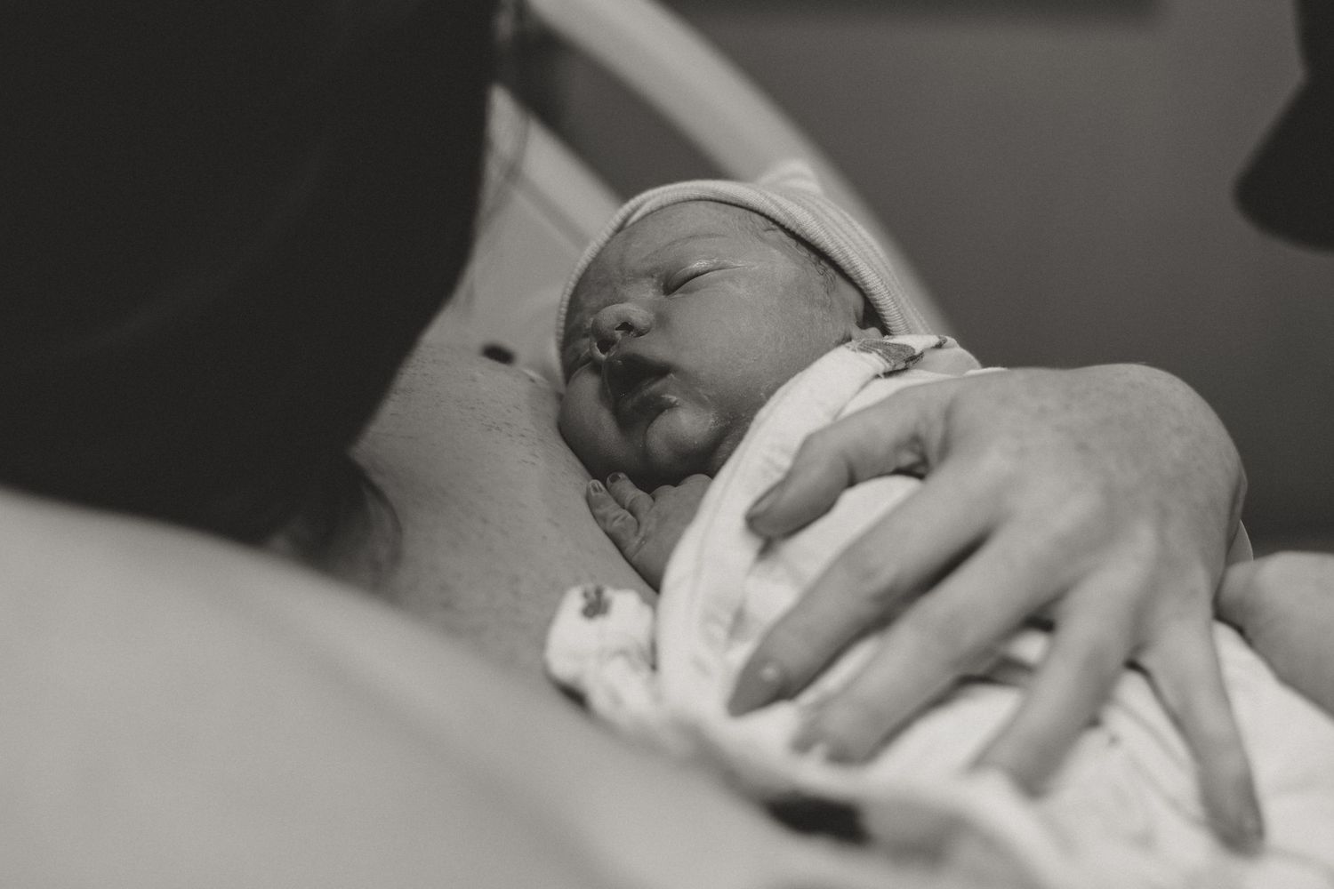 A black and white image of a newborn baby being held and cared for in a medical setting.