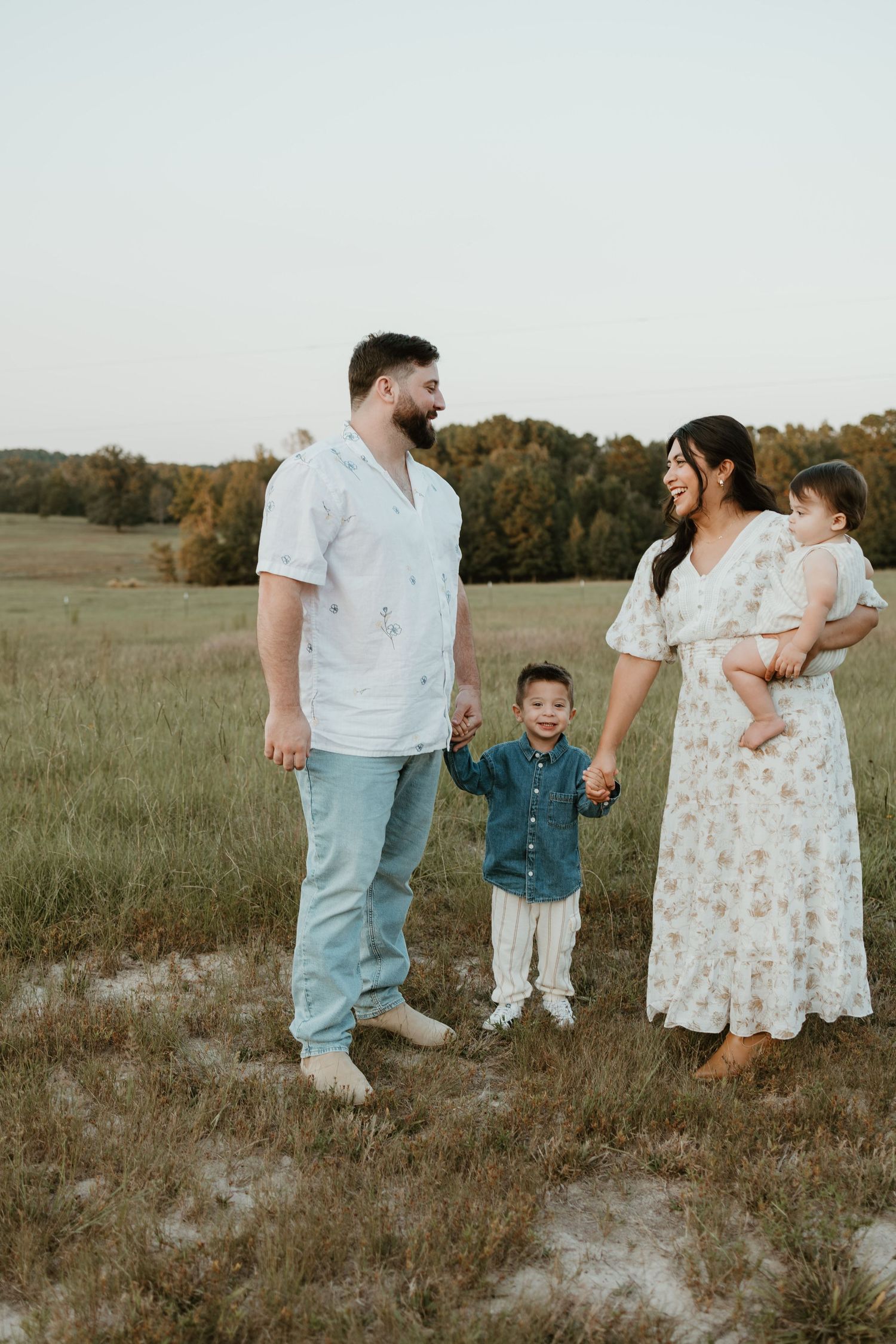 Beautiful family photos showing a couple and child bonding together in a serene field at sunset.