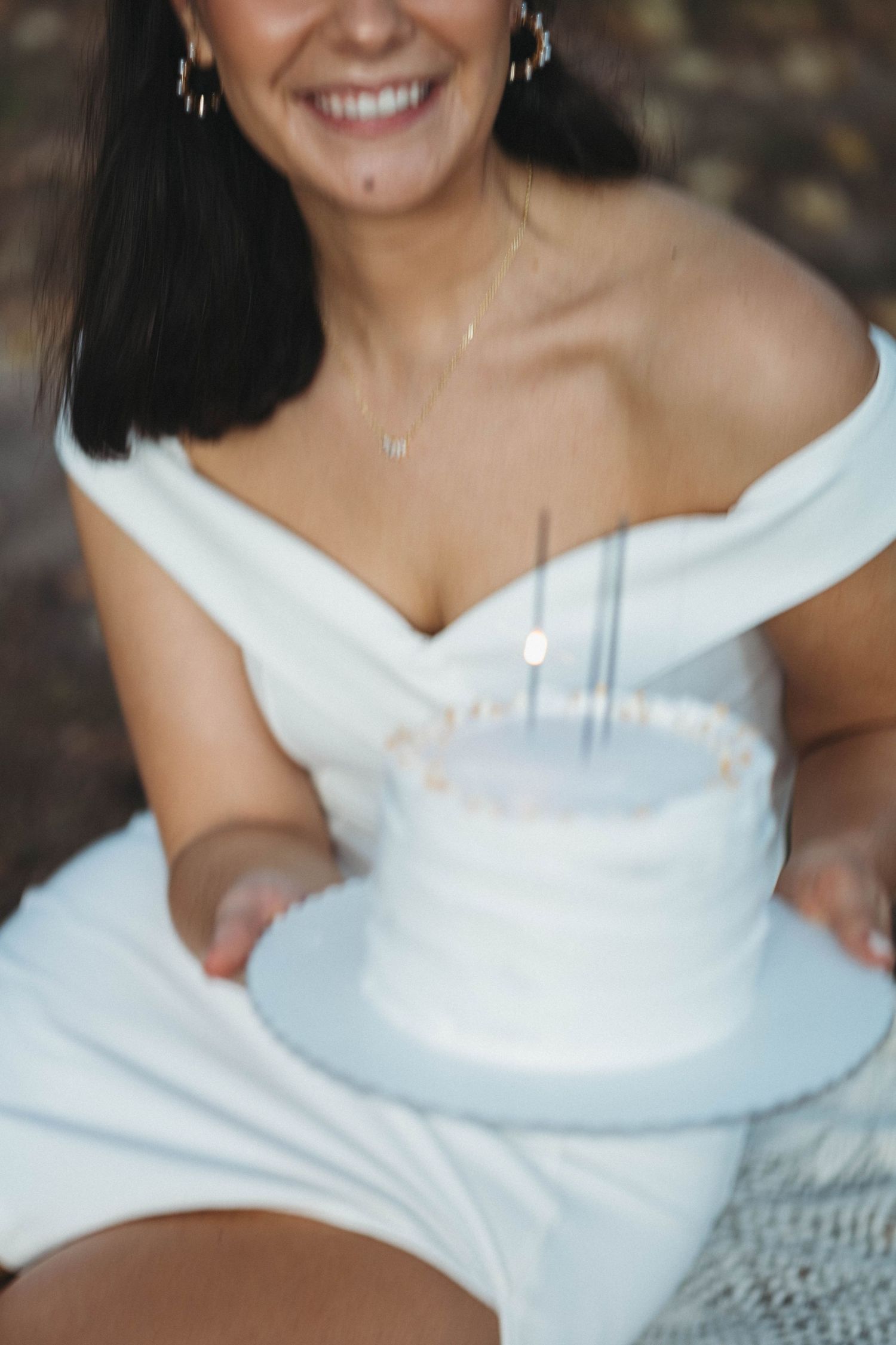 A white wedding dress detail with a dramatic off-shoulder neckline designed in an architectural folded style.