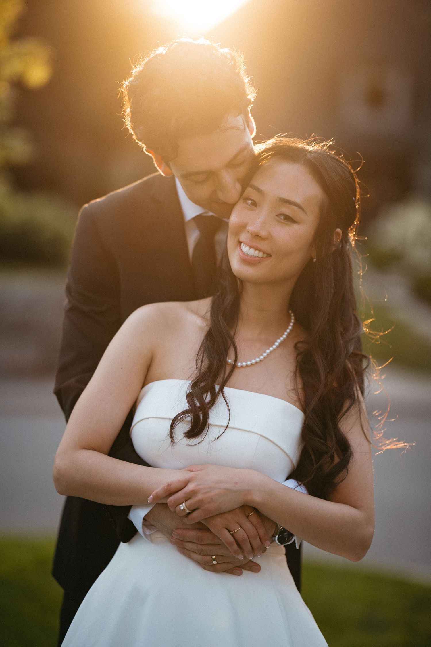A romantic golden hour wedding photo series captures a couple embracing outdoors with sunlit backlighting.