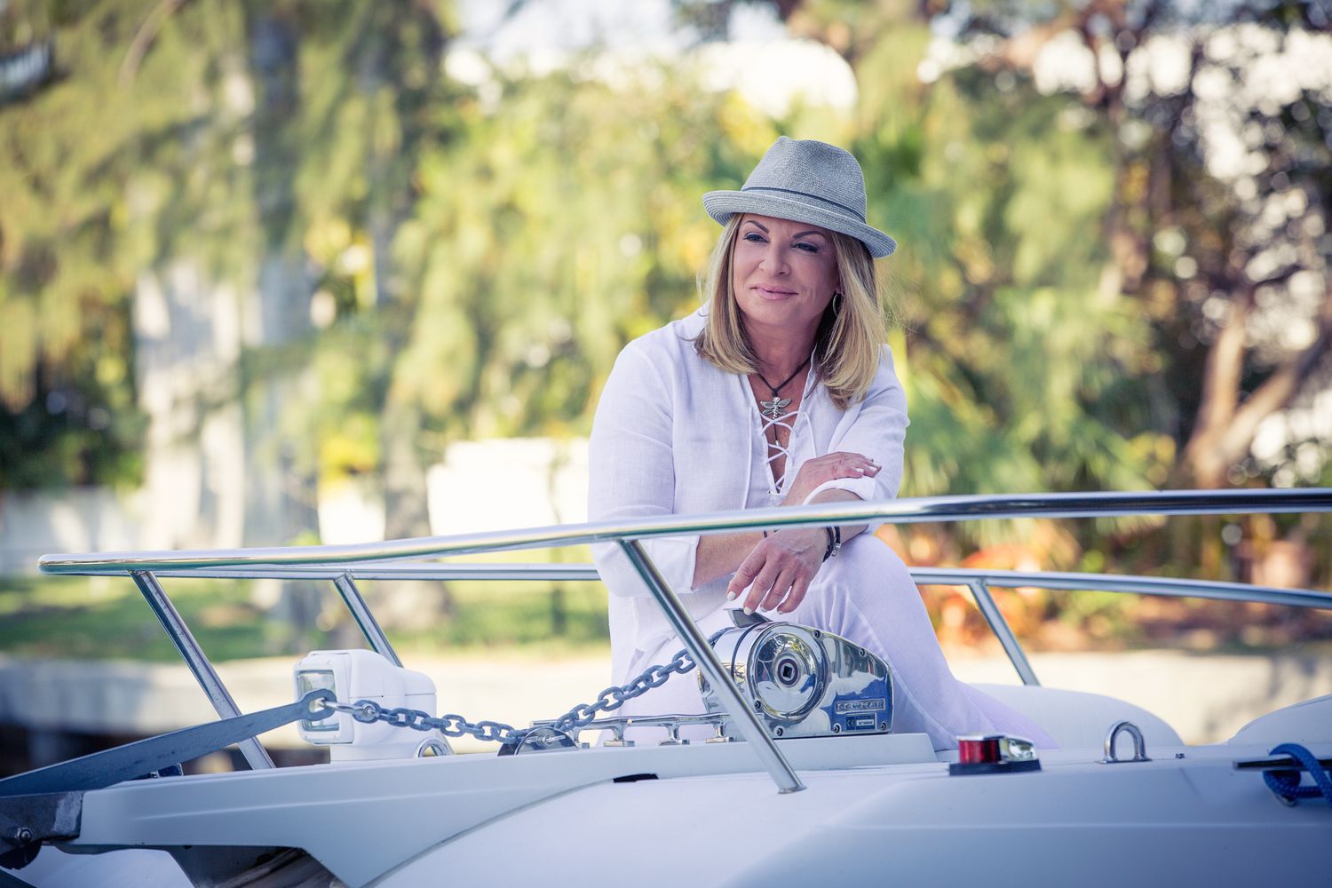 Dra. Ana Maria Polo from Caso Cerrado in a white outfit and hat sitting at helm of boat on sunny day in a miami lifestyle photography shoot