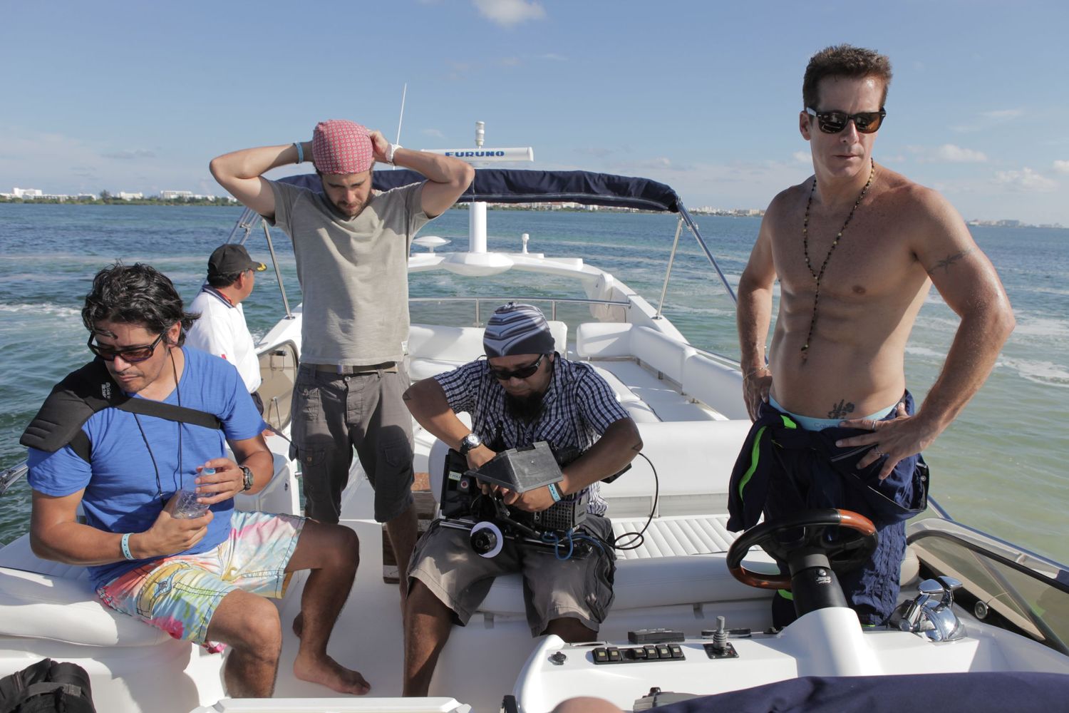 Group relaxing on a boat deck during sunny day on the water in a behind the scenes set photography session in miami