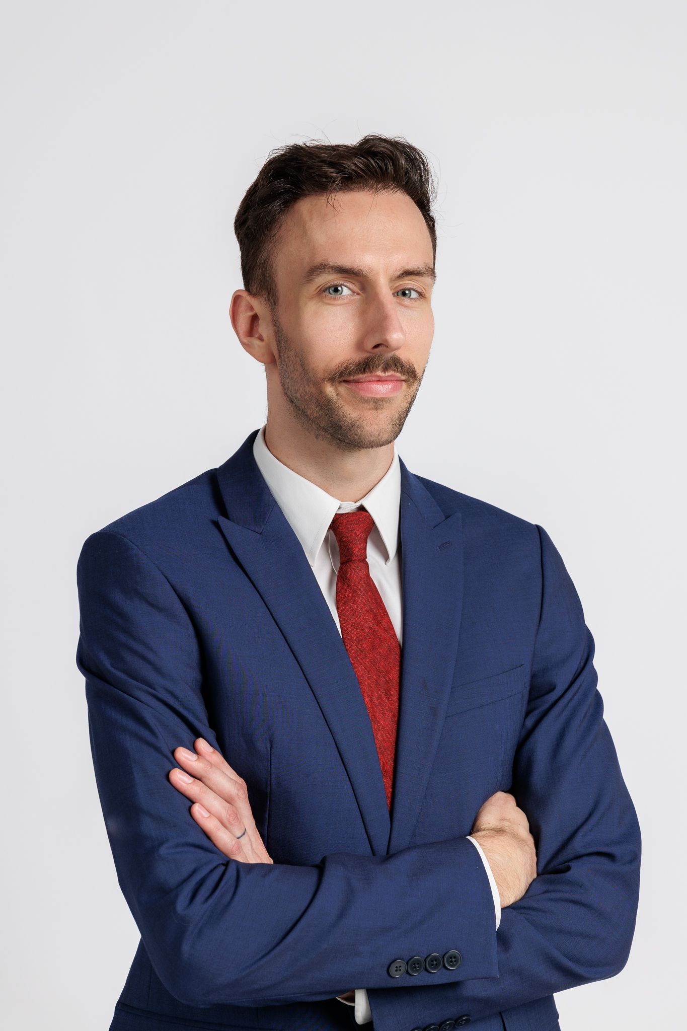 Business portrait of person in navy suit with arms crossed against white backdrop in a miami portrait photography & headshot photoshoot