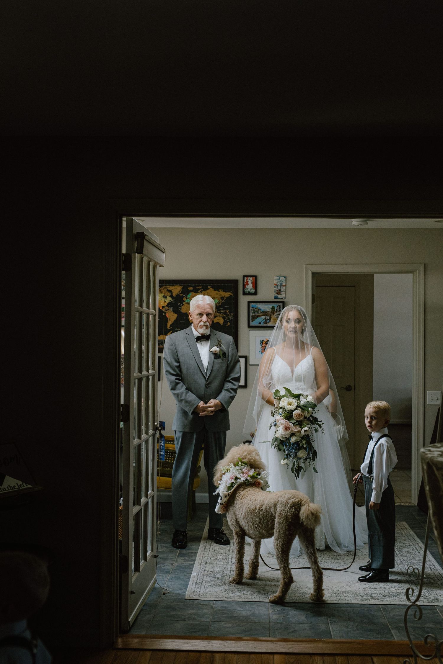 Wedding scene with bridal party and dog gathered in doorway of home.