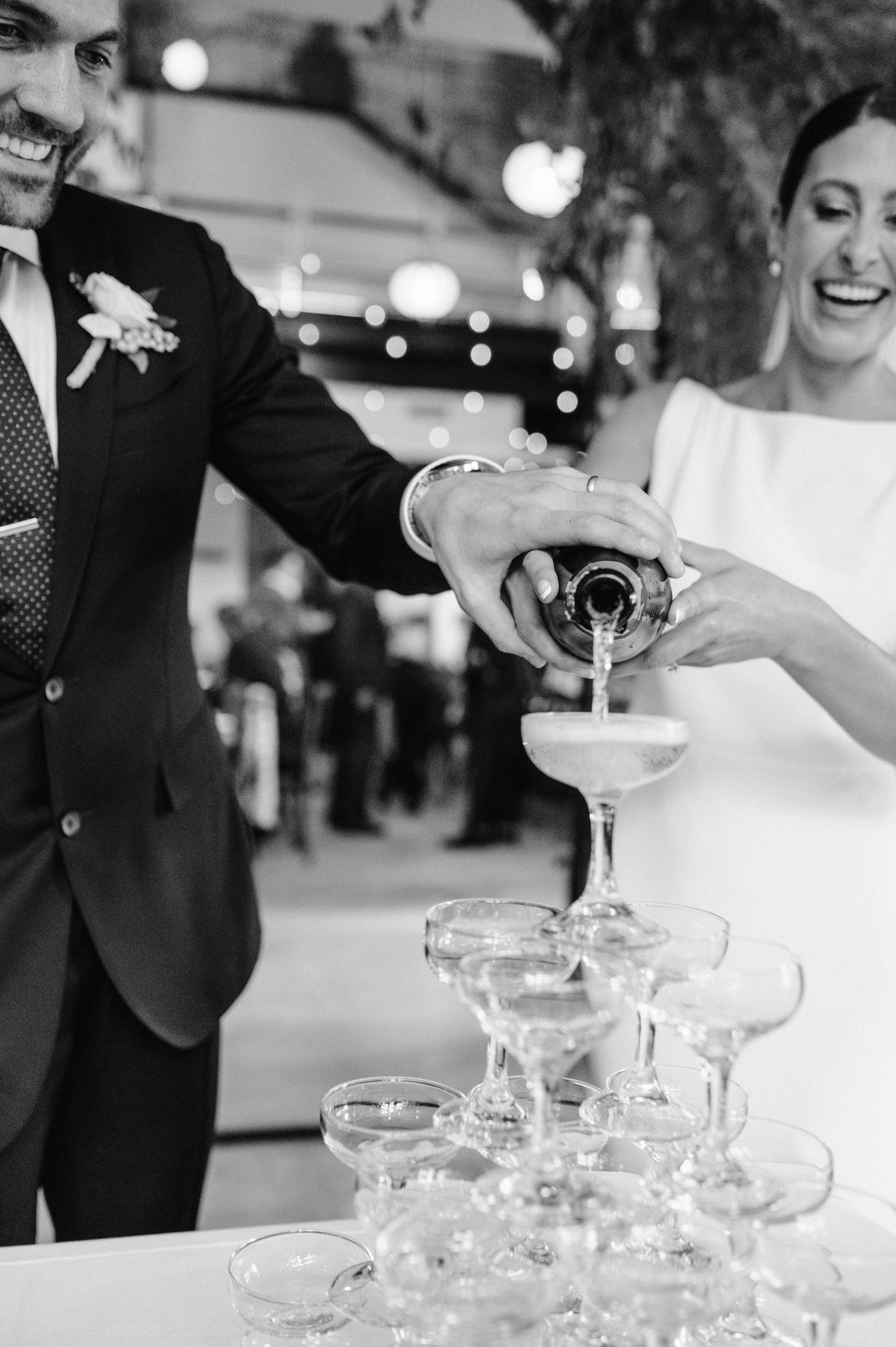 Celebratory moment of pouring champagne into a tower of glasses at an elegant wedding reception.