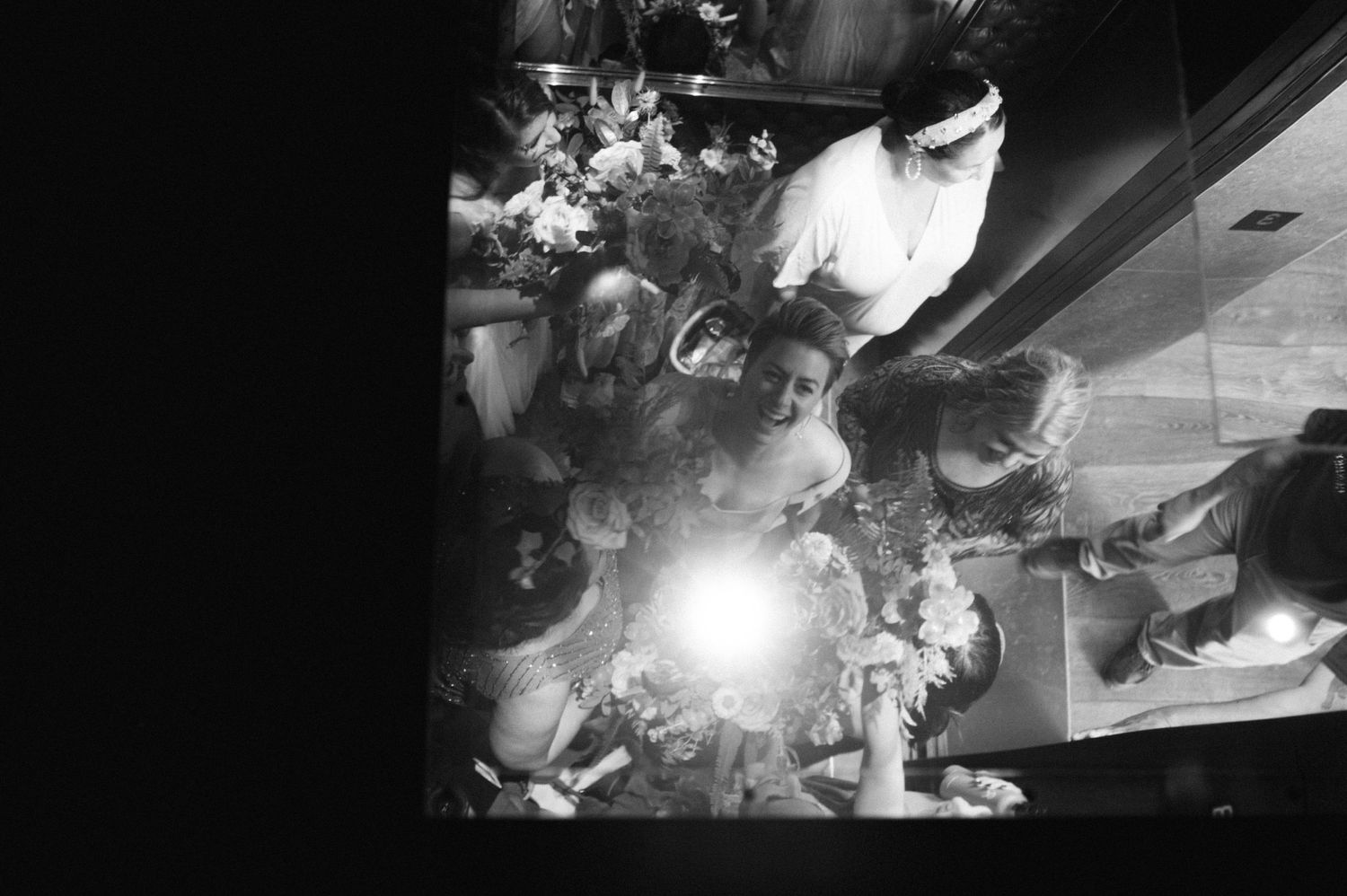 A black and white overhead shot of a crowded celebration with dramatic lighting.