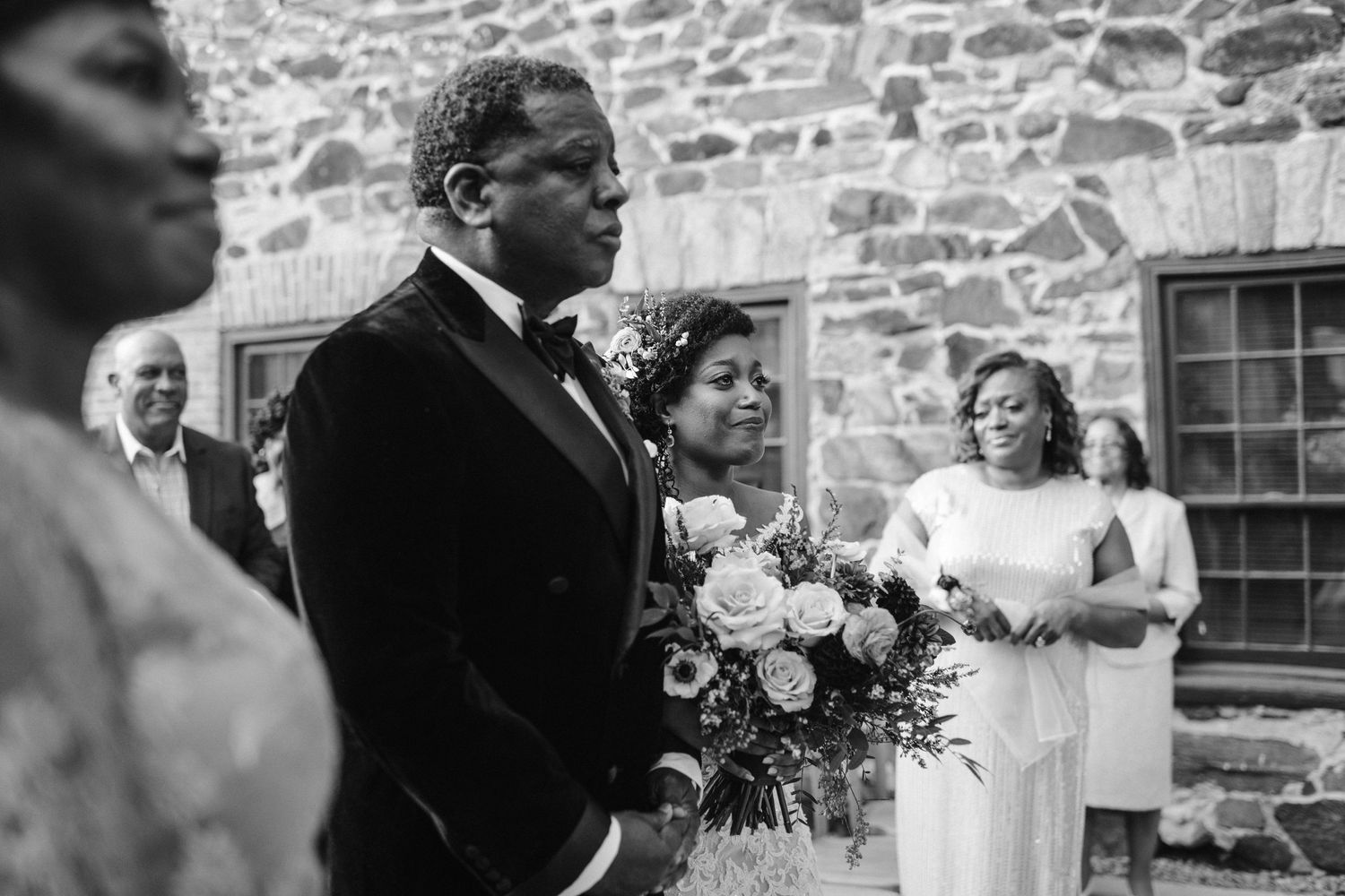 A wedding ceremony taking place in front of a rustic stone wall.