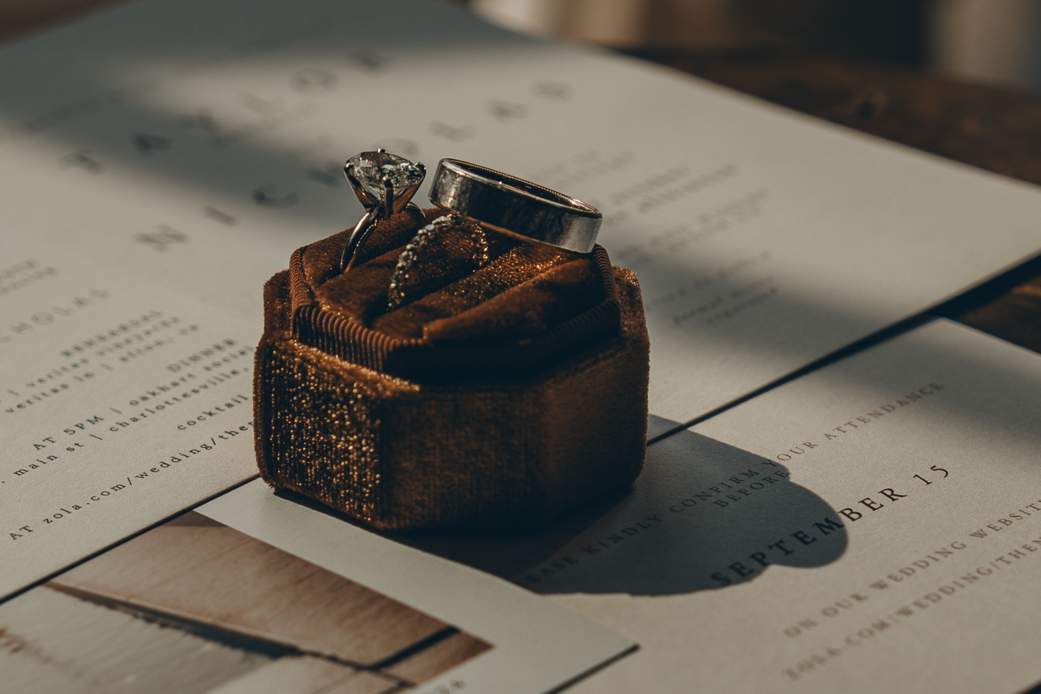 Vintage bronze metal inkwell casting dramatic shadows on paper documents in warm moody lighting.
