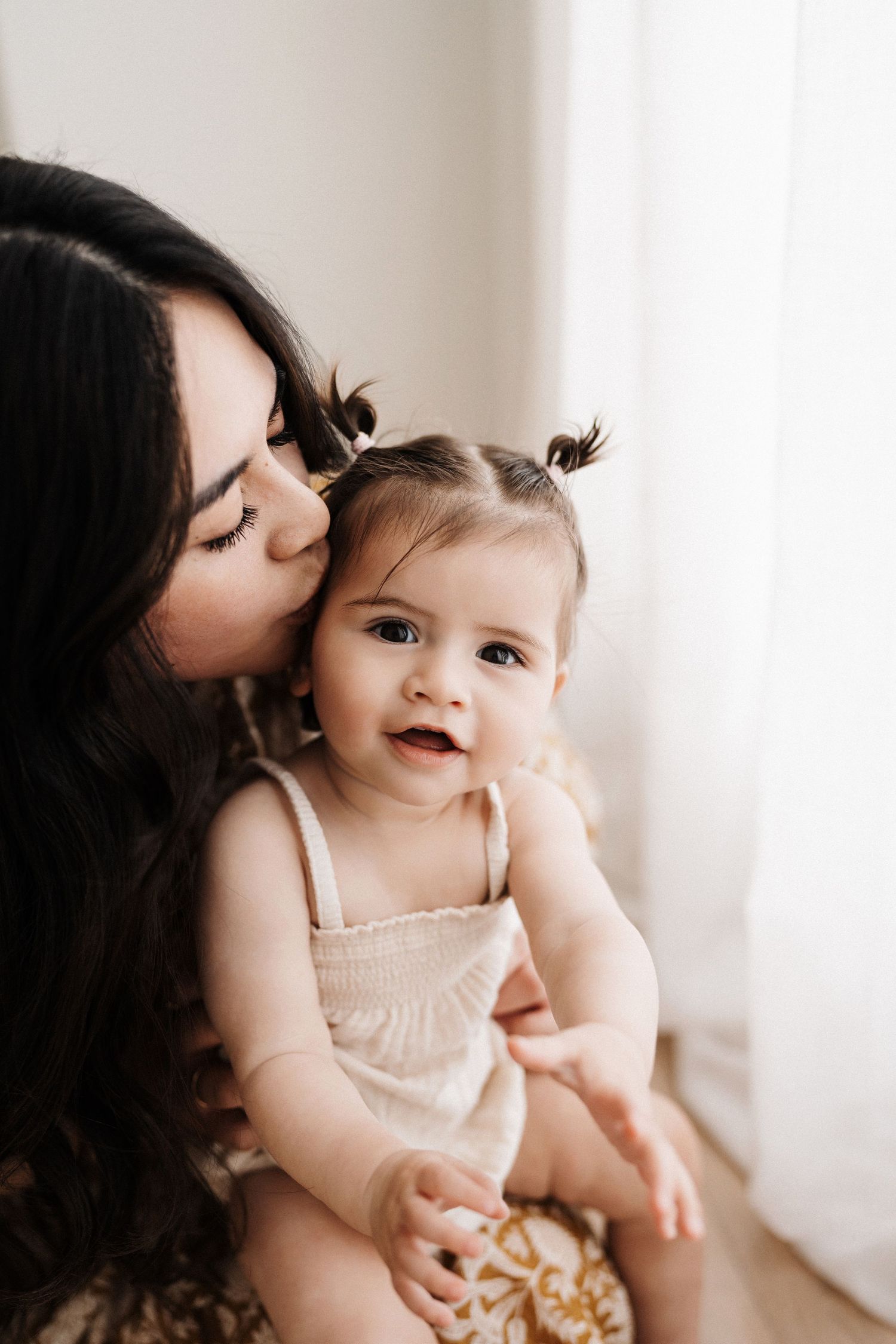 Sweet candid moments between mother and baby in white studio setting.