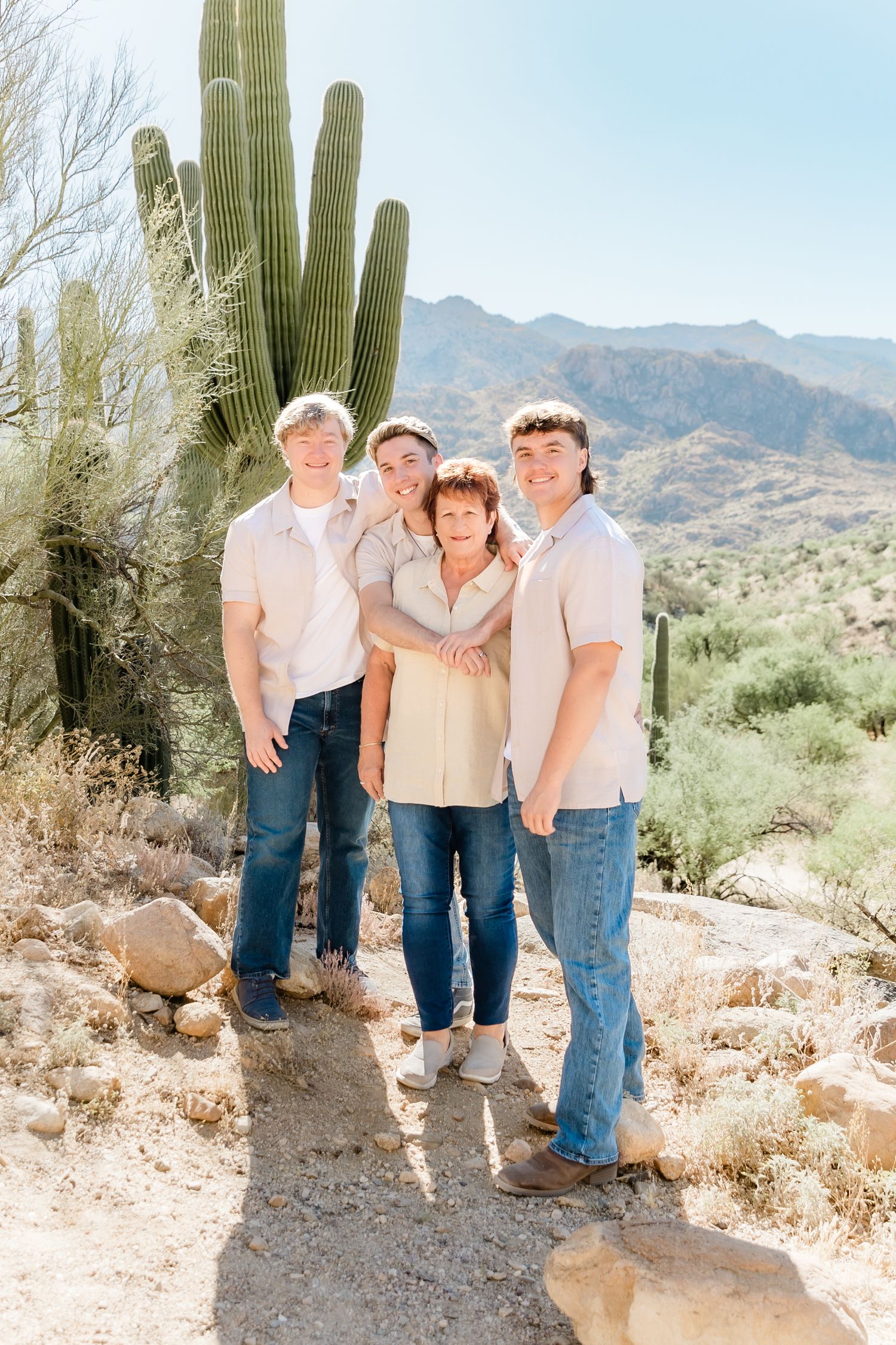 Group photo against desert mountain backdrop with tall saguaro cactus.