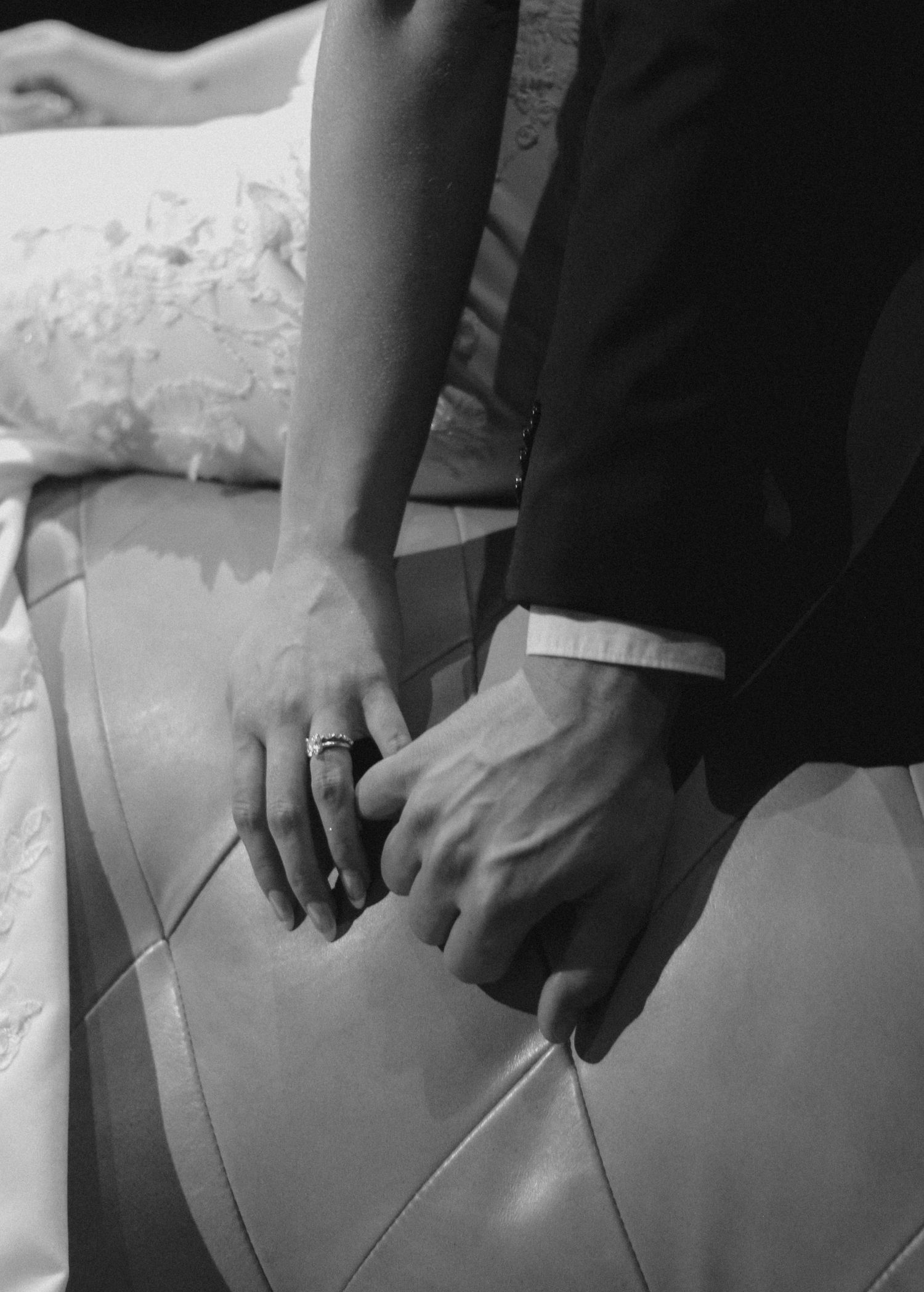 Black and white close-up of hands resting on a textured surface showing rings.