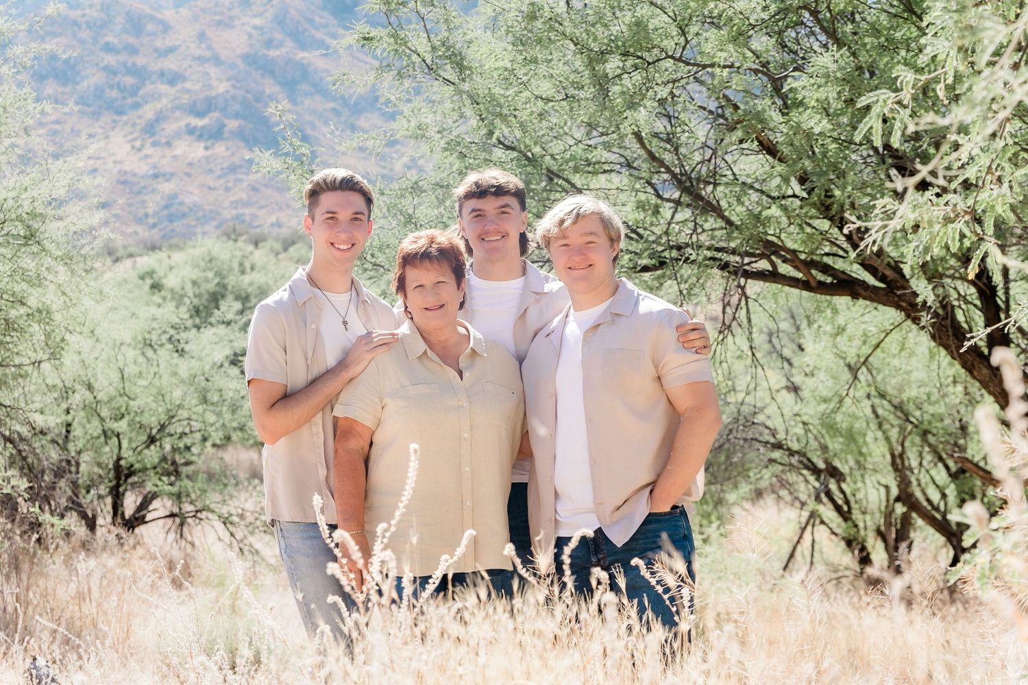 Family portrait in desert landscape with mountains and desert brush in the background.
