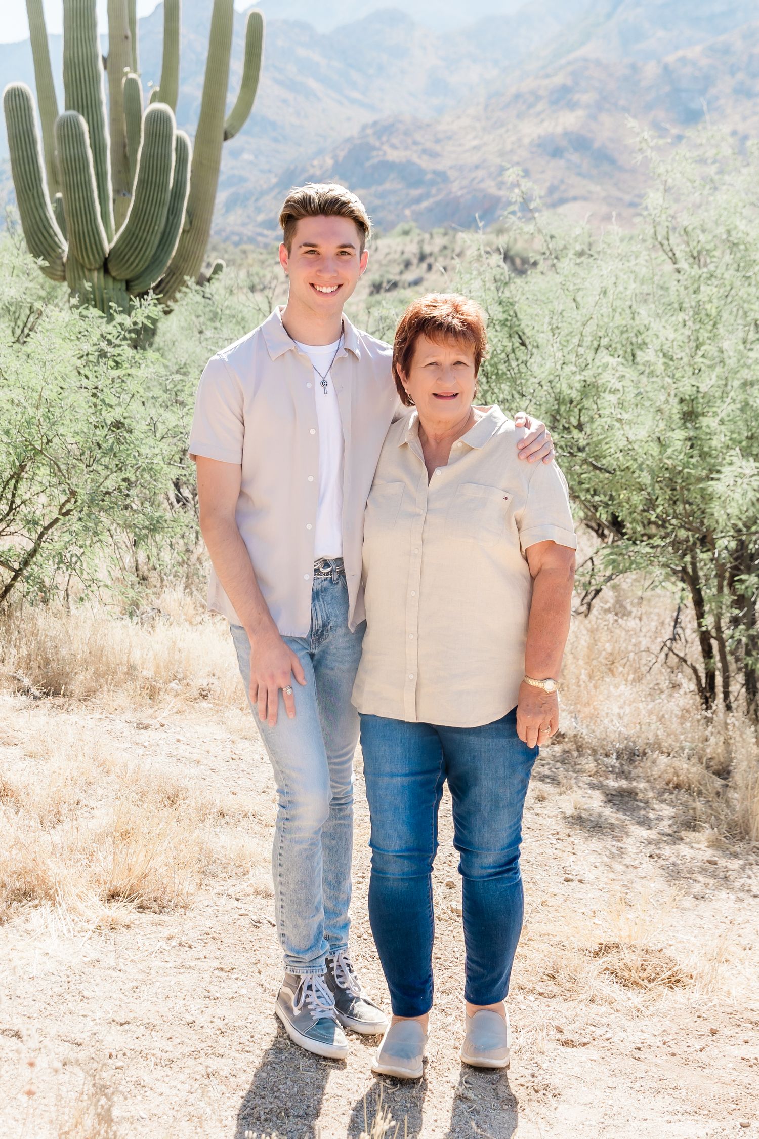 Casual outdoor photo with saguaro cactus and desert mountains in background.