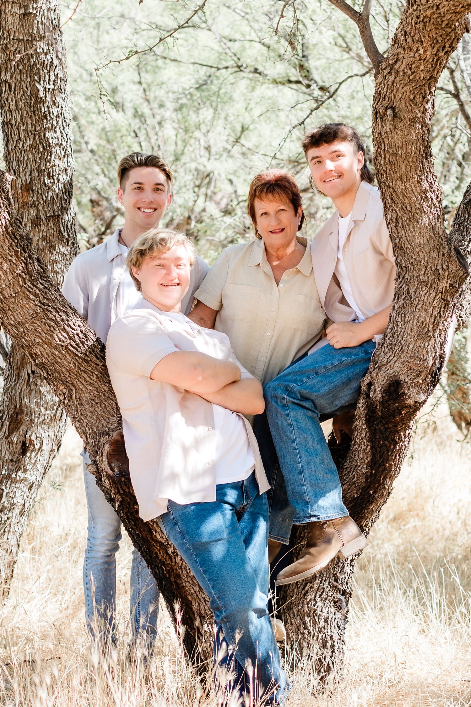 Group portrait of four people posed in a tree with natural desert backdrop.