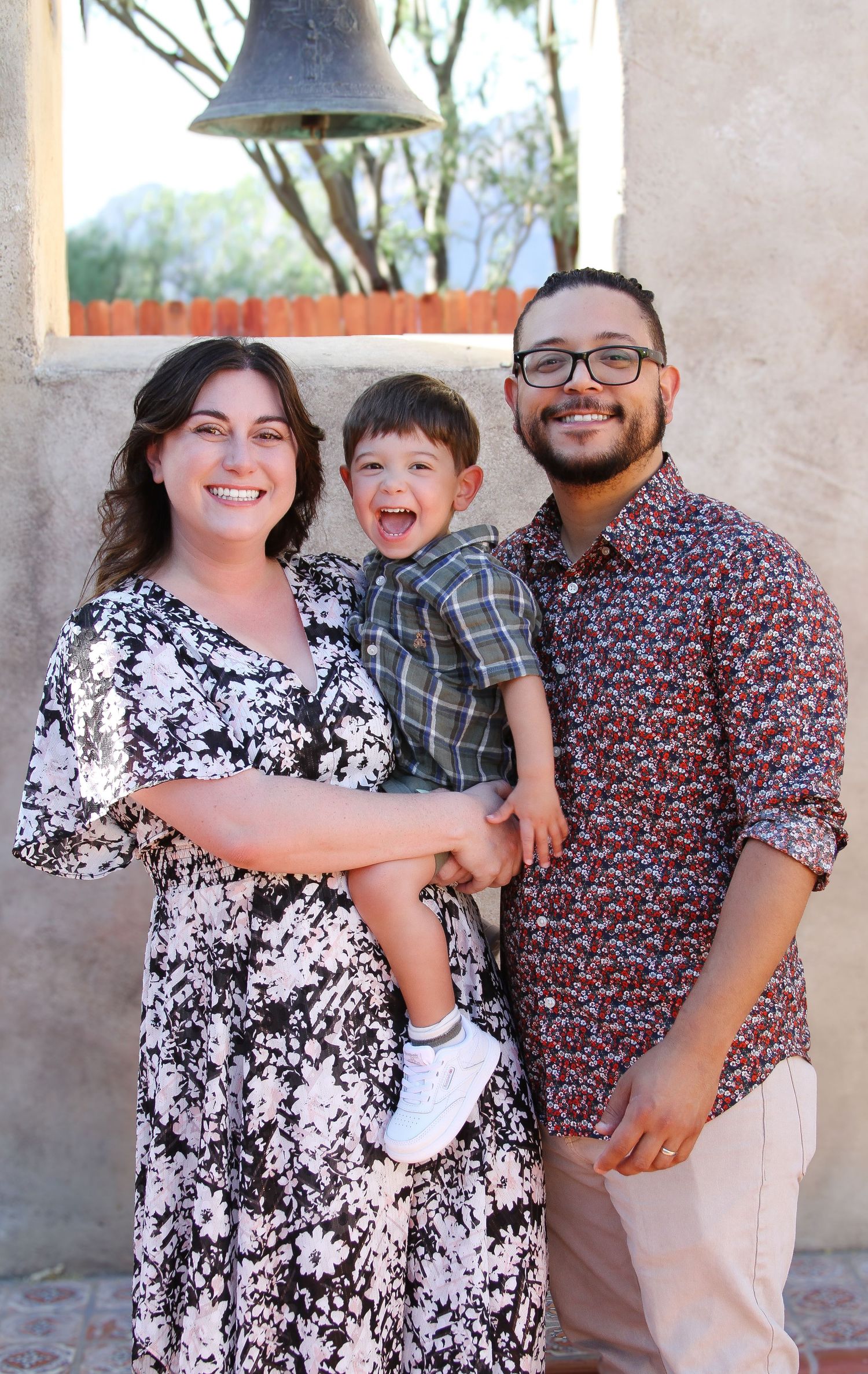 Happy family portrait under bell against stucco wall.