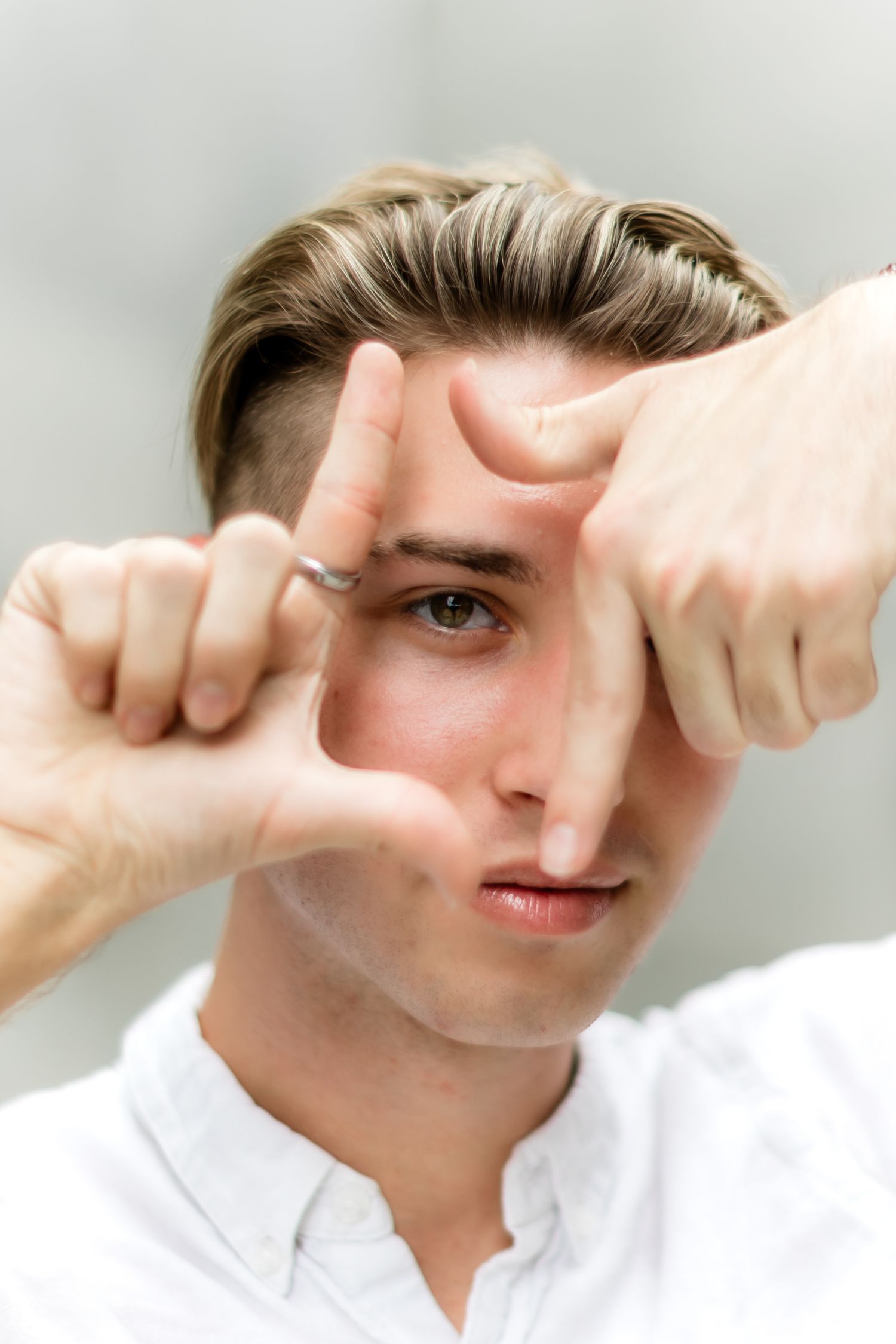 Person framing eye with fingers while making creative portrait gesture.