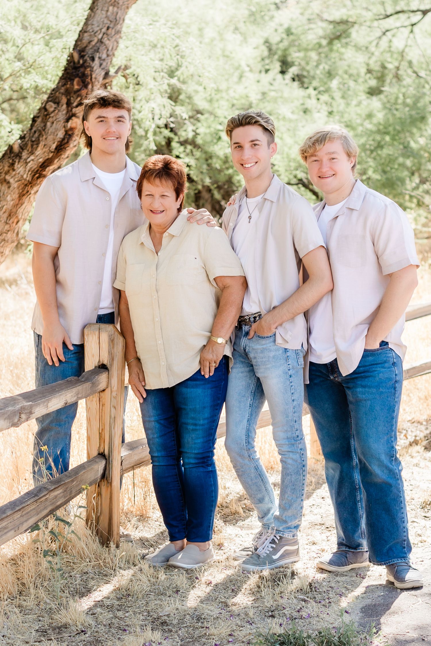Casual group photo by wooden fence in sunlit desert landscape.