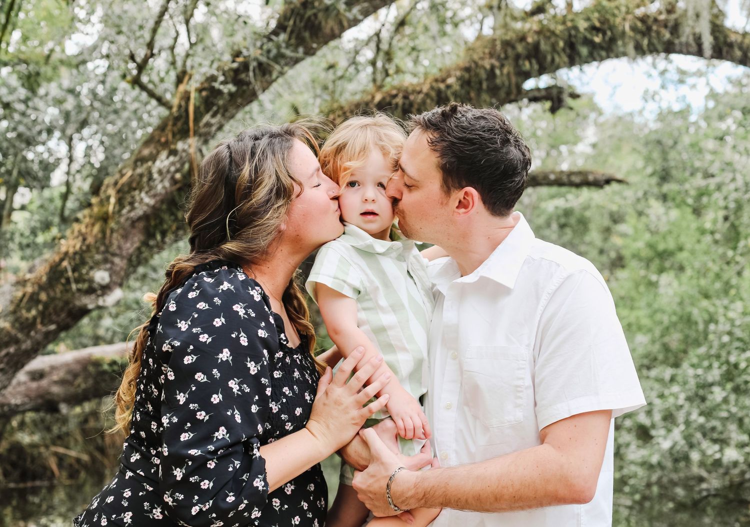 A sweet candid moment of a mom and dad kissing their son during their family session in estero