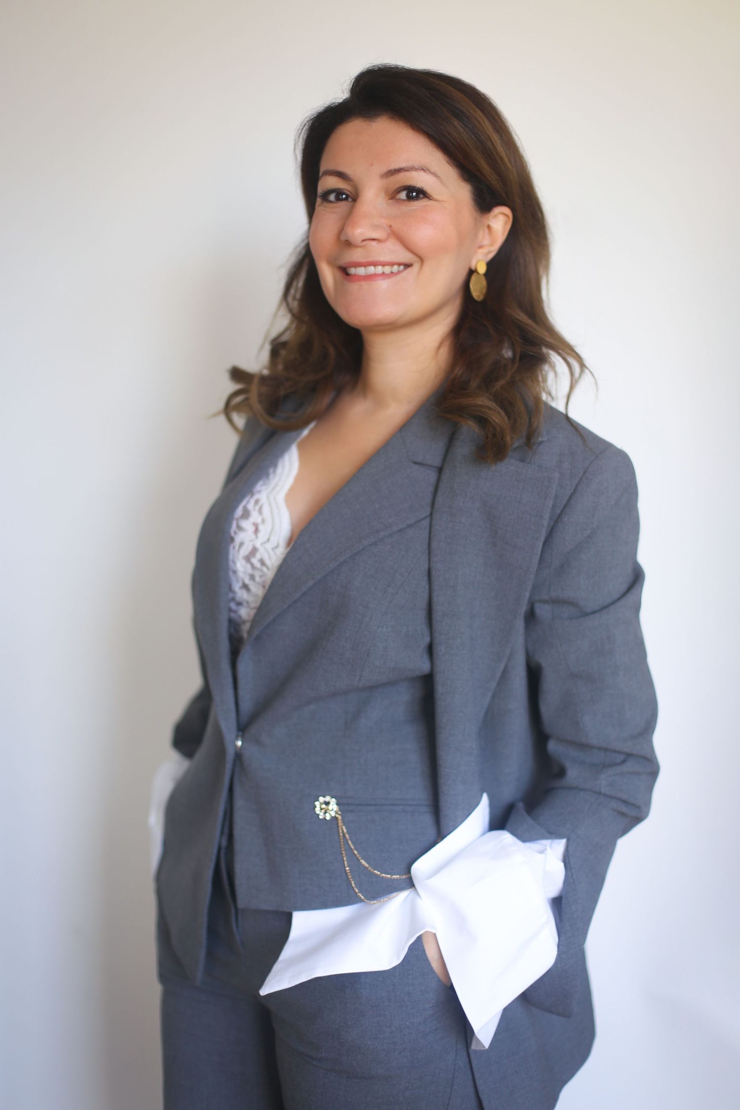 Professional wearing a gray business suit and white blouse in a corporate headshot.