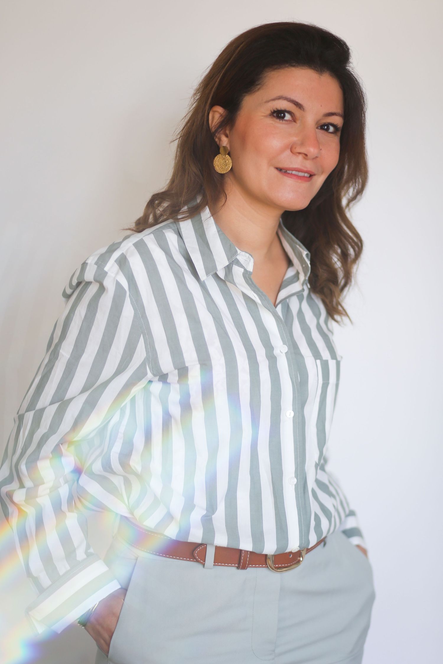 Professional wearing striped button-down shirt and khaki pants in studio setting with light effects.