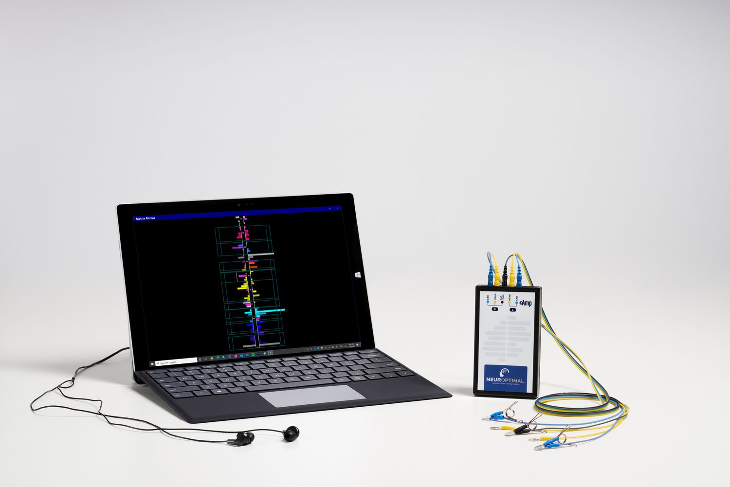 A laptop computer displaying waveform data connected to a medical monitoring device with cables on a white surface.