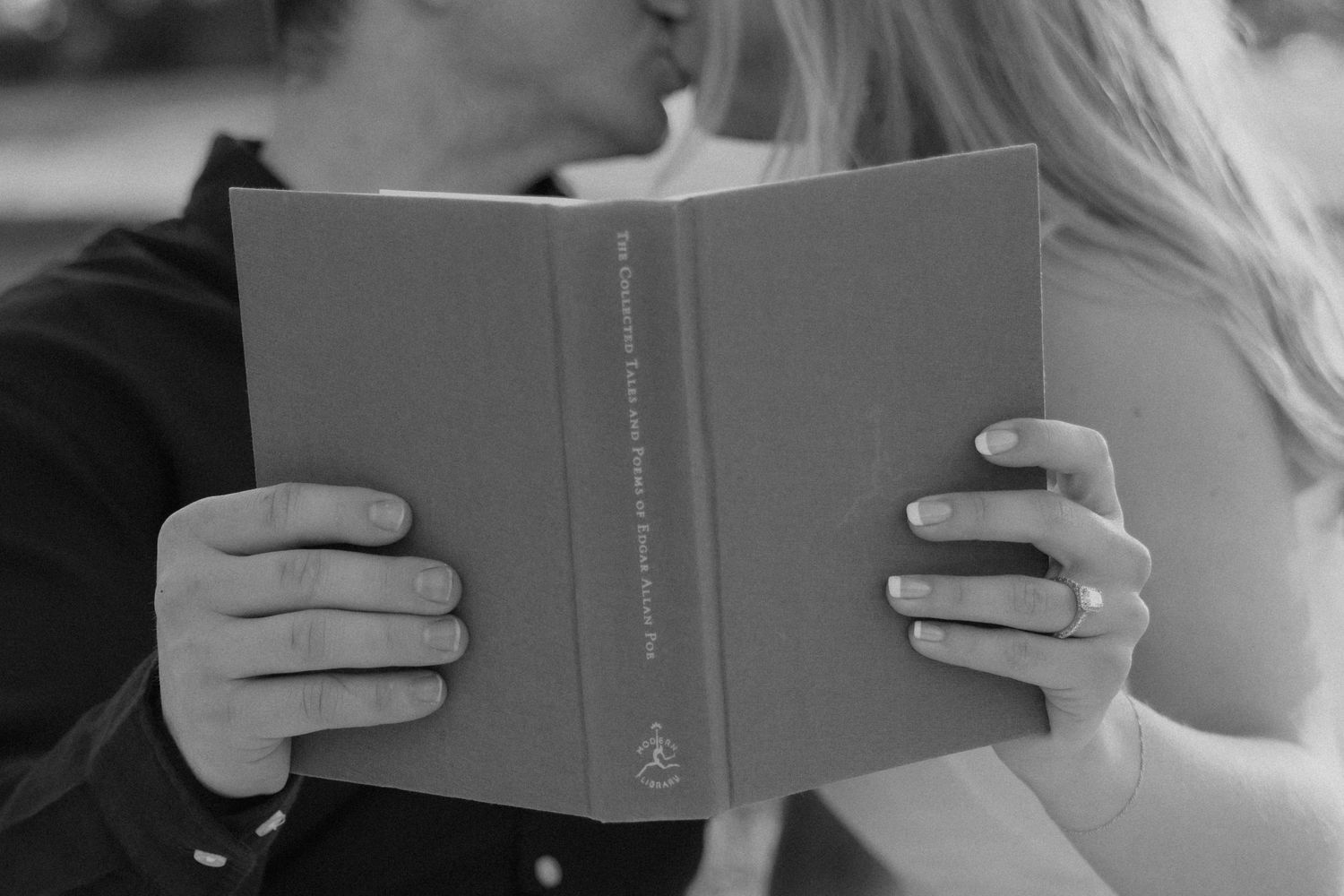 Couple sharing a moment while reading a book together in black and white.