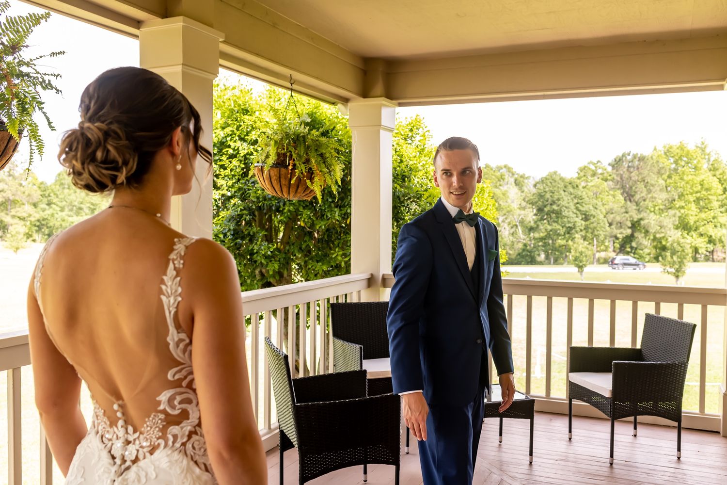 Wedding couple stands on balcony overlooking scenic view during outdoor reception celebration.